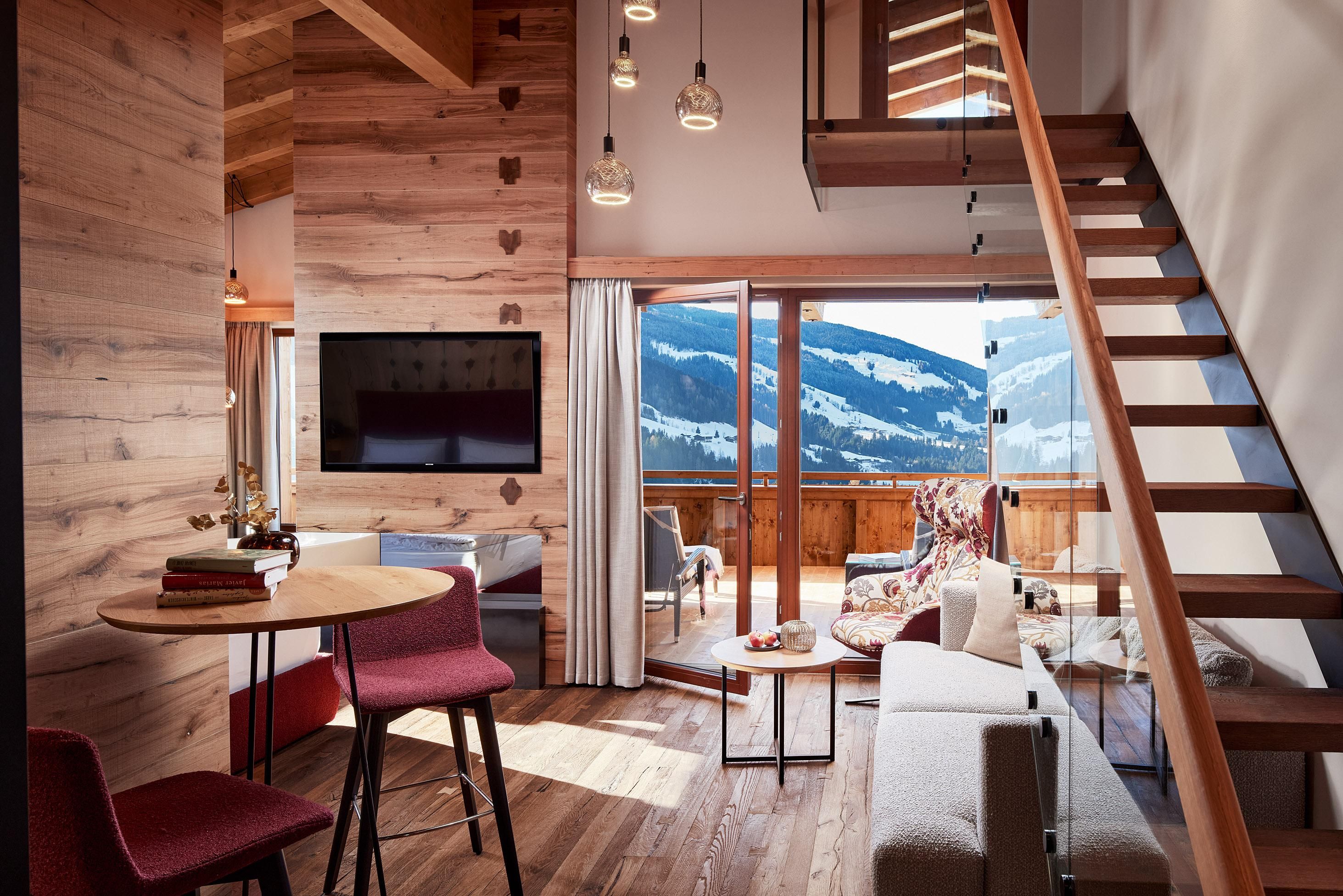 A modern living environment with wood paneling and large windows. The interior design offers a view of the mountains and a cozy atmosphere.