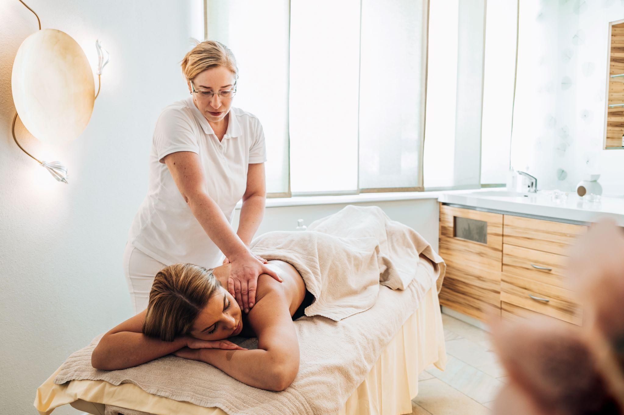 A woman receives a massage in a modern wellness room. The atmosphere seems relaxed and calming.