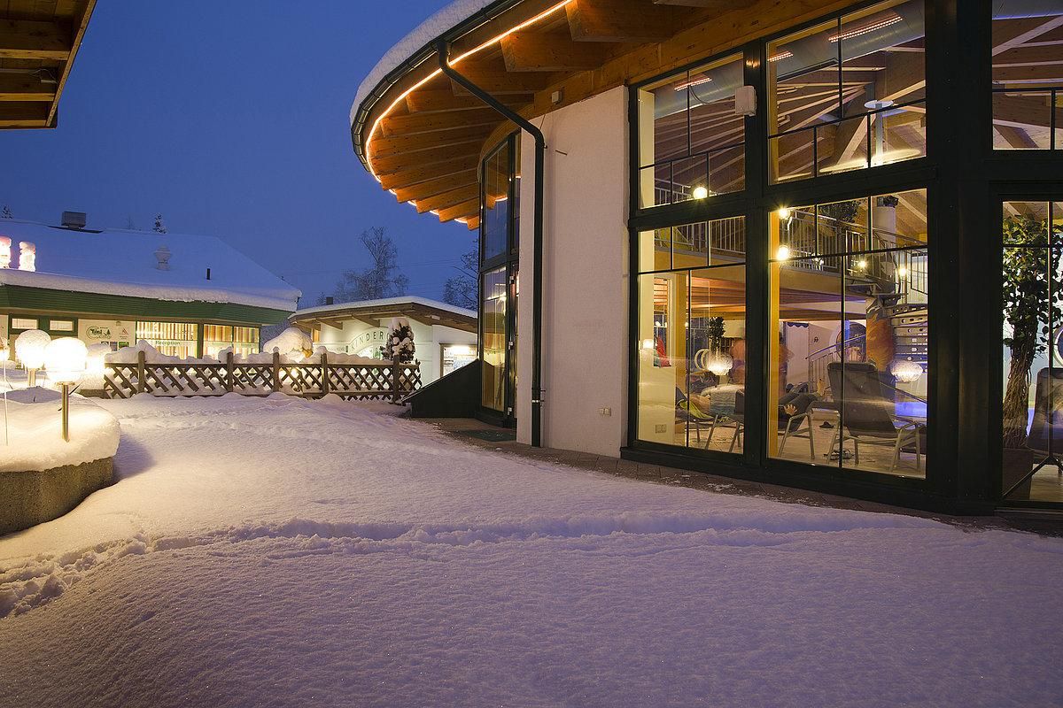 A modern building in the snow at night. The area is festively lit and conveys a cozy atmosphere.