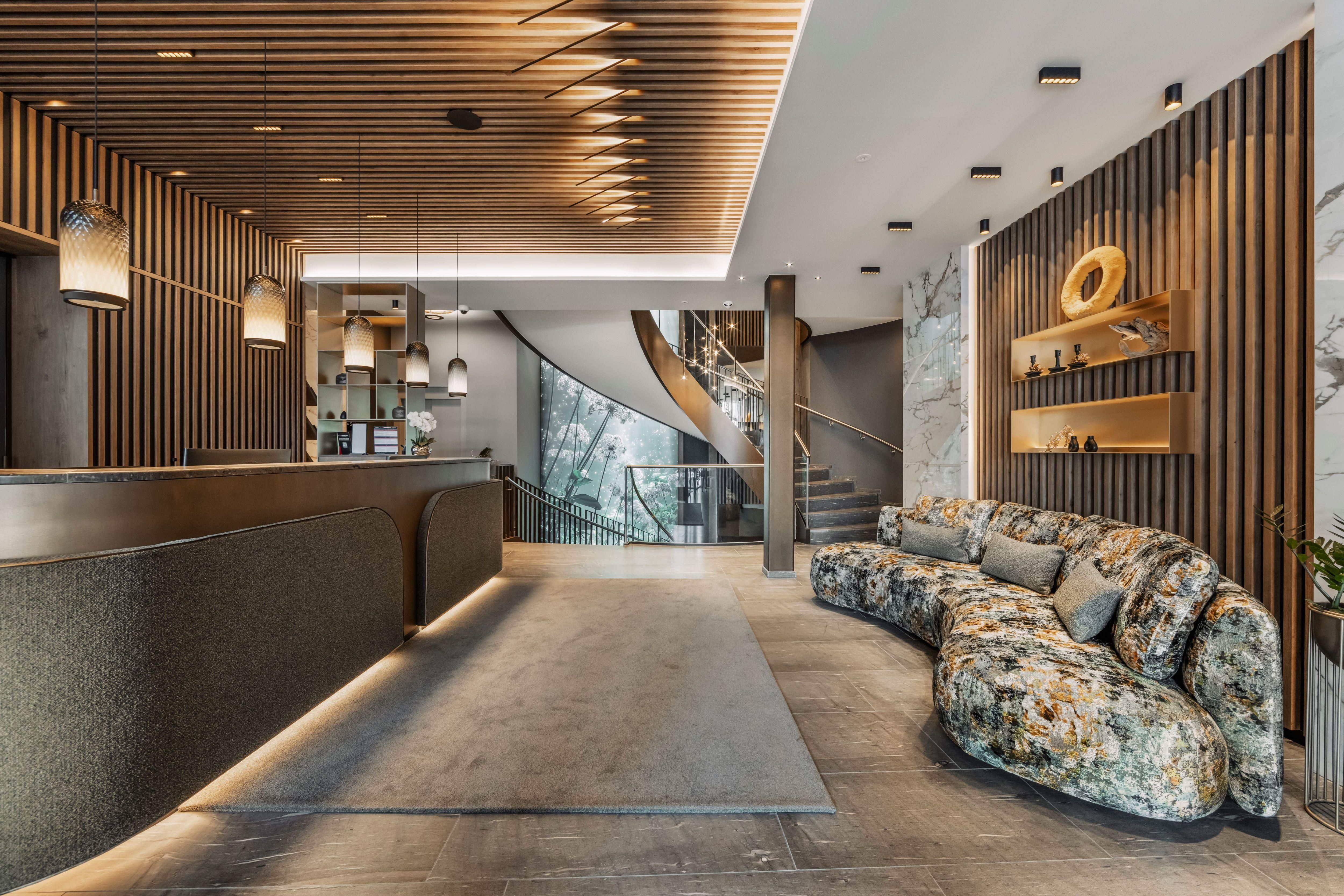 A modern reception area featuring a long counter and an inviting seating corner. The walls are adorned with wooden paneling and decorative elements.