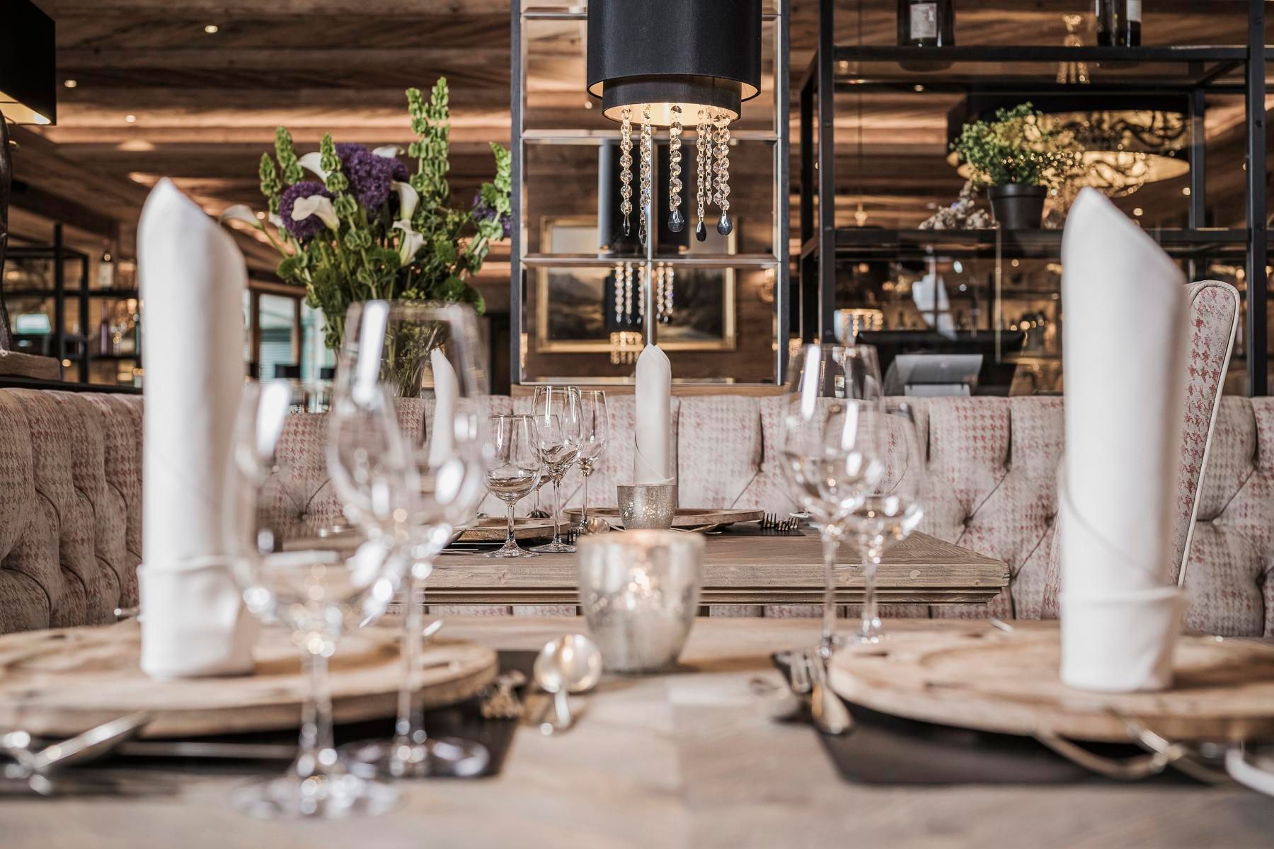 An elegant set table in a modern restaurant. The tables are arranged with glasses, cutlery, and decorative napkins.