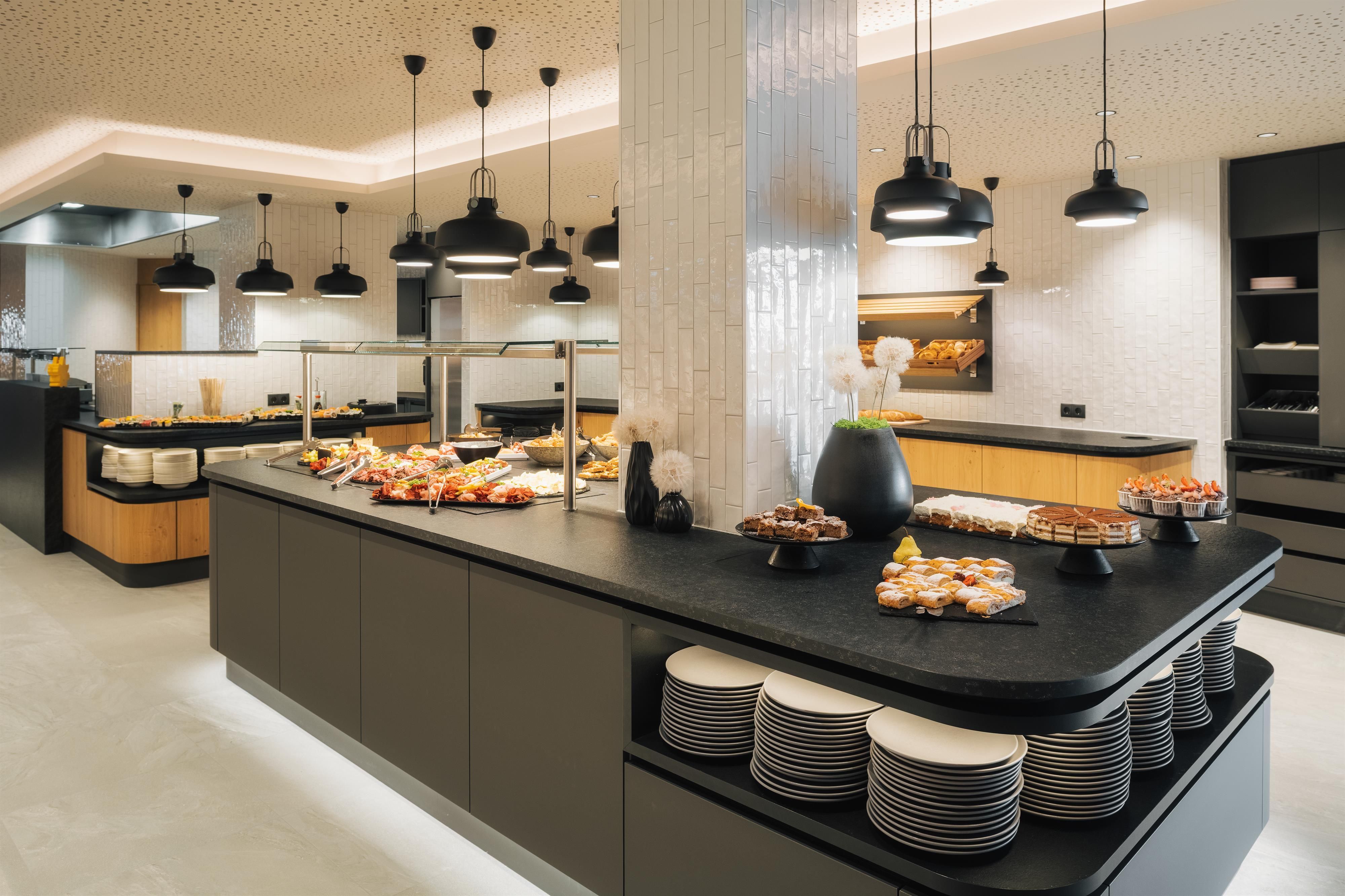 An elegant buffet area with various dishes and desserts. The modern decor and subtle lighting create an inviting atmosphere.