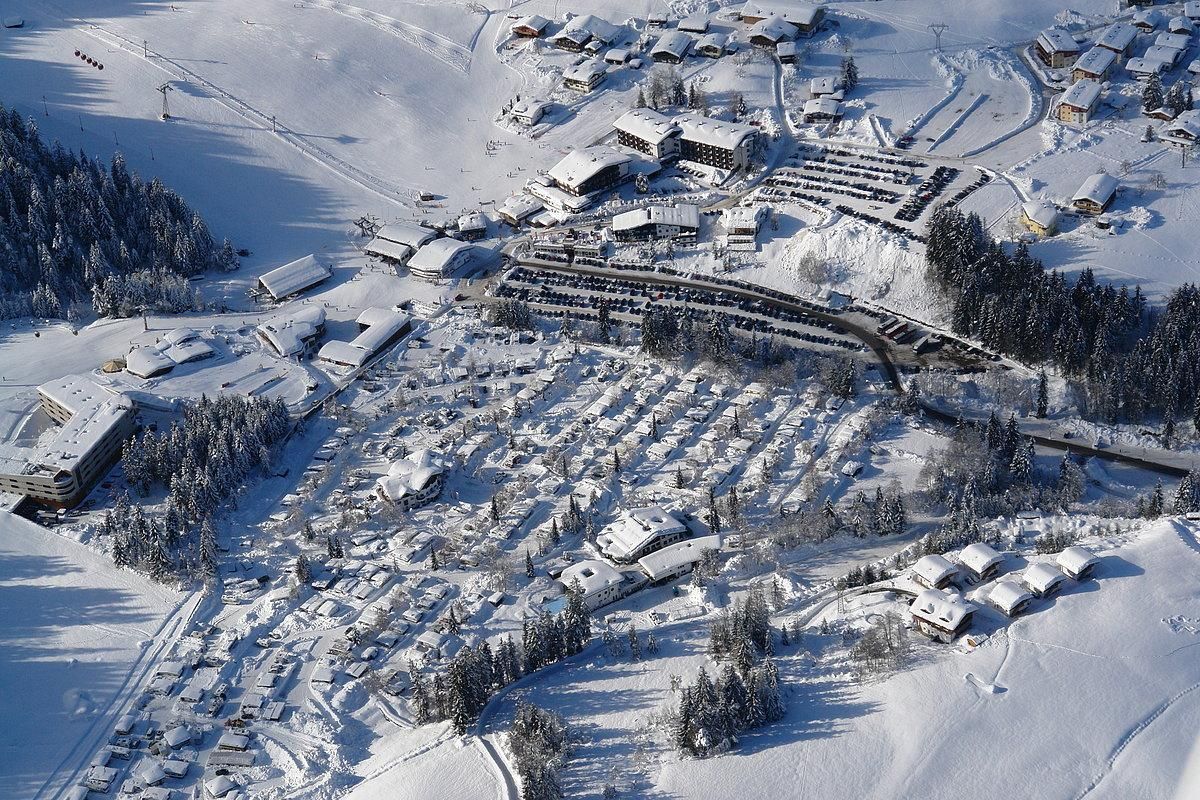 A snow-covered mountain landscape with many houses and cabins. The landscape is calm and wintry, perfect for a skiing holiday.