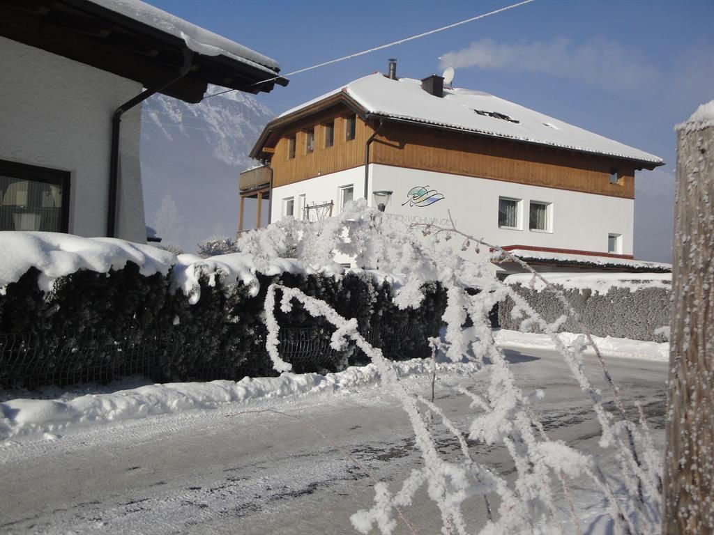 A snow-covered residential area with two different houses. The surroundings are wintry, and the landscape appears calm and peaceful.