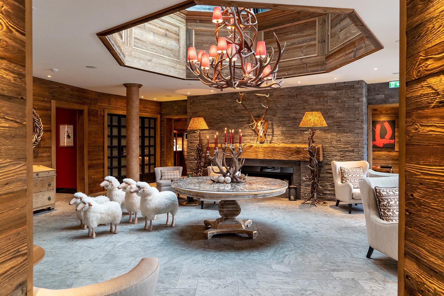 A stylish reception area with wooden elements and a modern chandelier. Several sheep are standing around an elegant table in the center of the room.