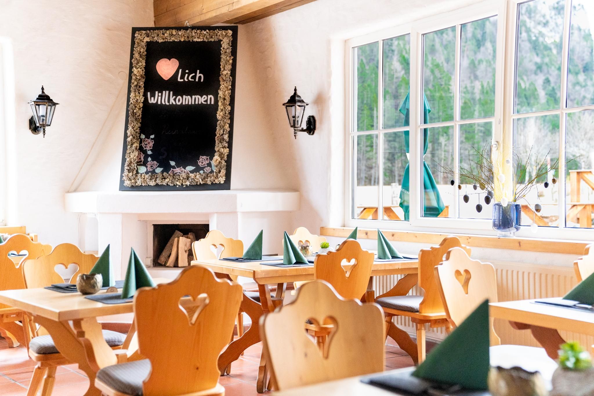 An inviting restaurant with wooden chairs and tables. On the wall, there is a board that says "Welcome".