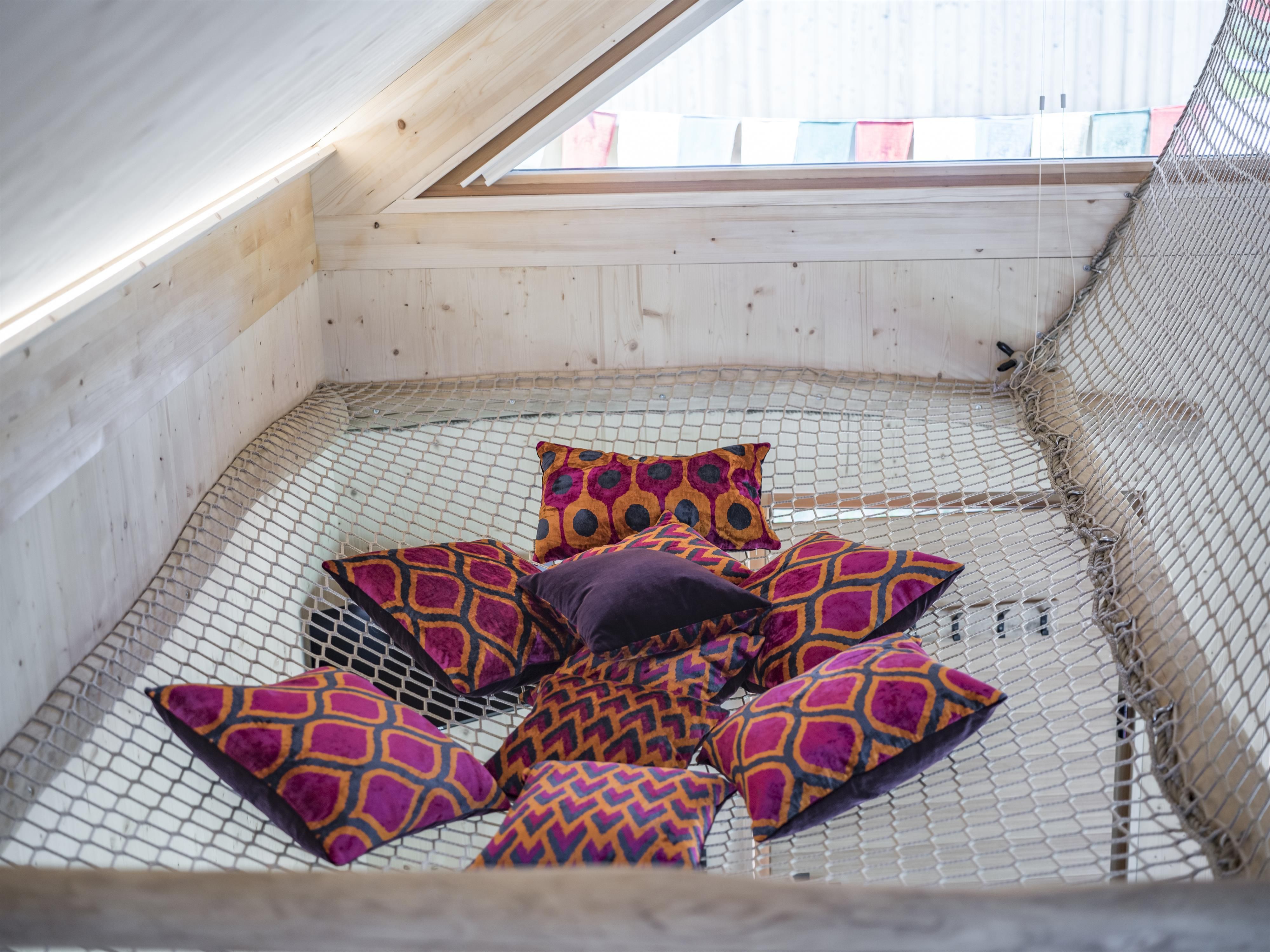 A cozy retreat with colorful cushions on a net. The bright, natural wood paneling creates an inviting atmosphere.