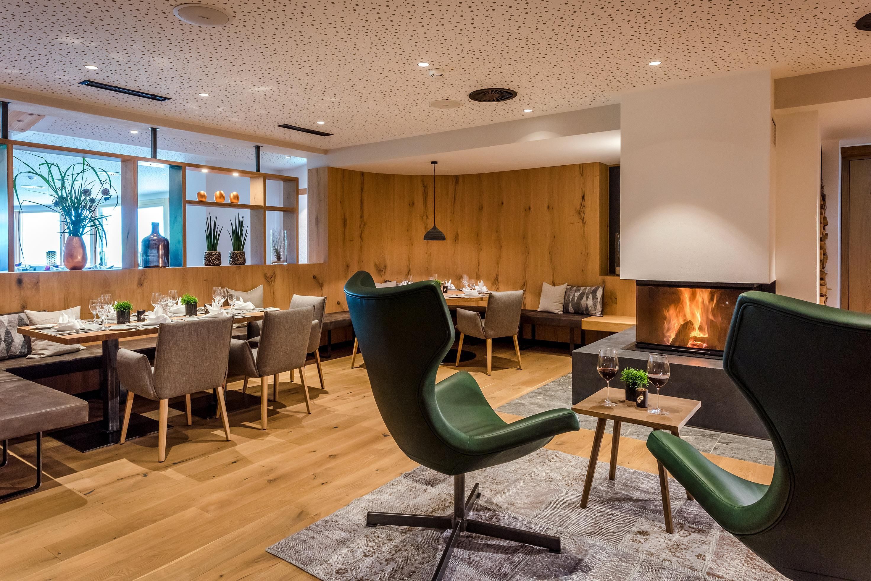 A modern restaurant with wooden paneling and elegant furniture. The fireplace creates a cozy atmosphere.