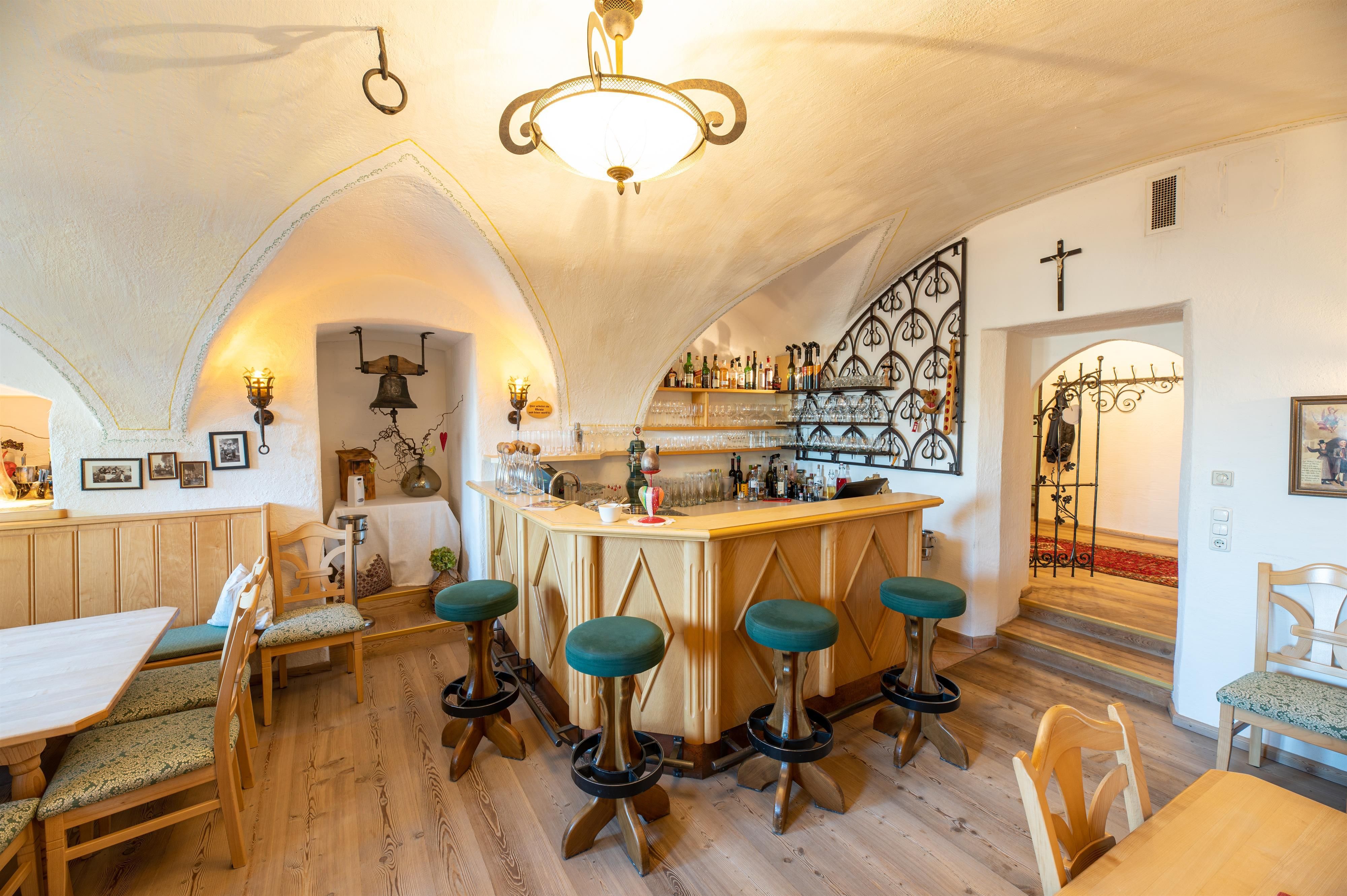 A cozy bar with a wooden counter and green bar stools. The atmosphere is warm and inviting in a stylish room.