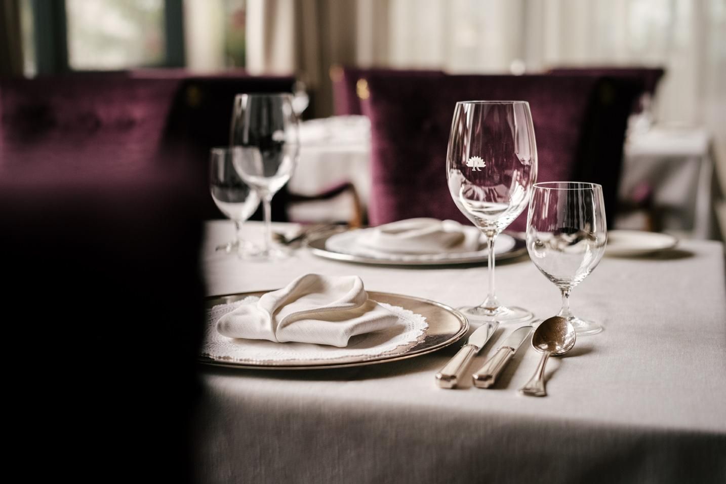An elegant table with shiny cutlery and crystal glasses. The tablecloth is set, and the atmosphere is stylish and inviting.