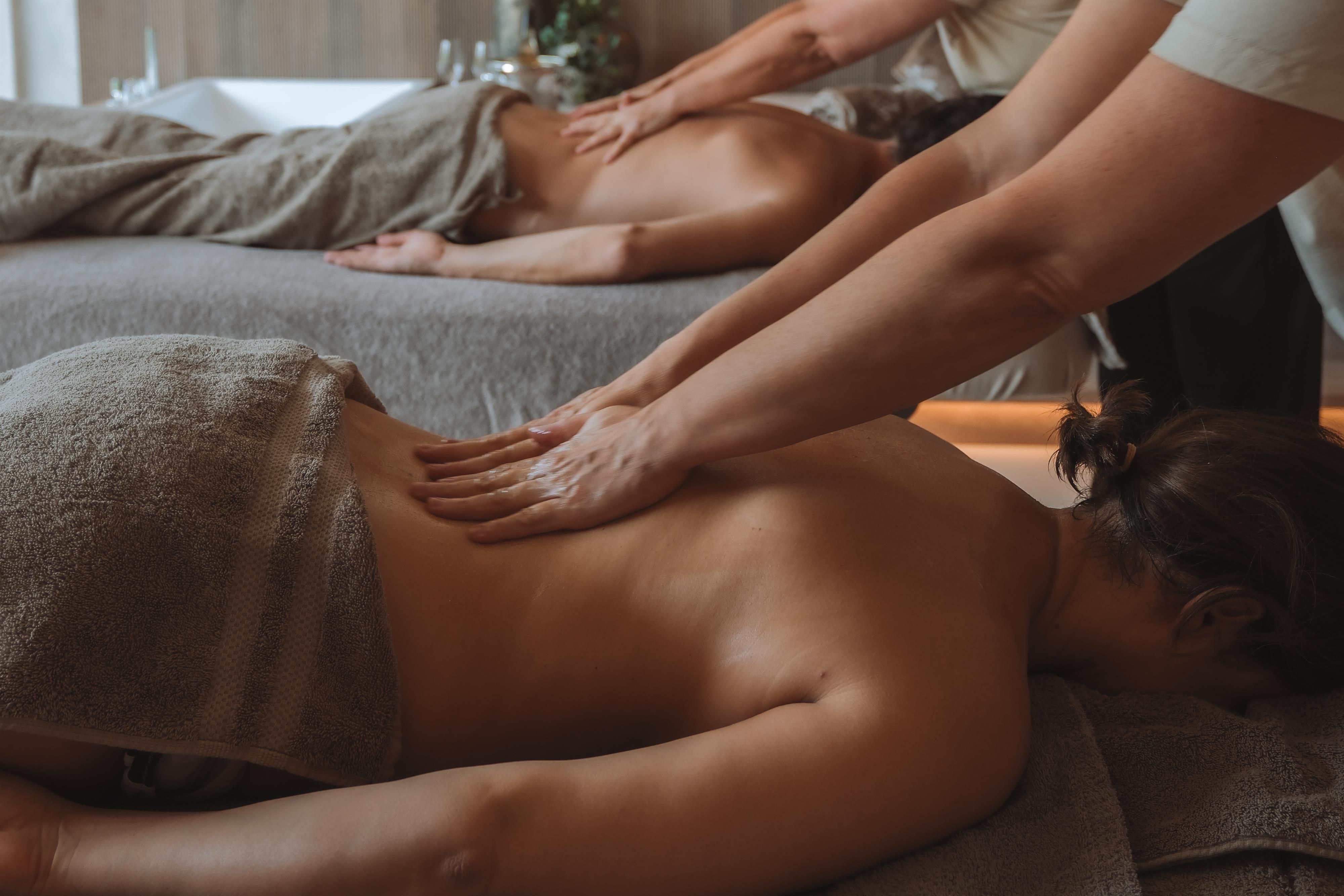 Two people are receiving a relaxing massage in a quiet room. The atmosphere is soothing and pleasant.