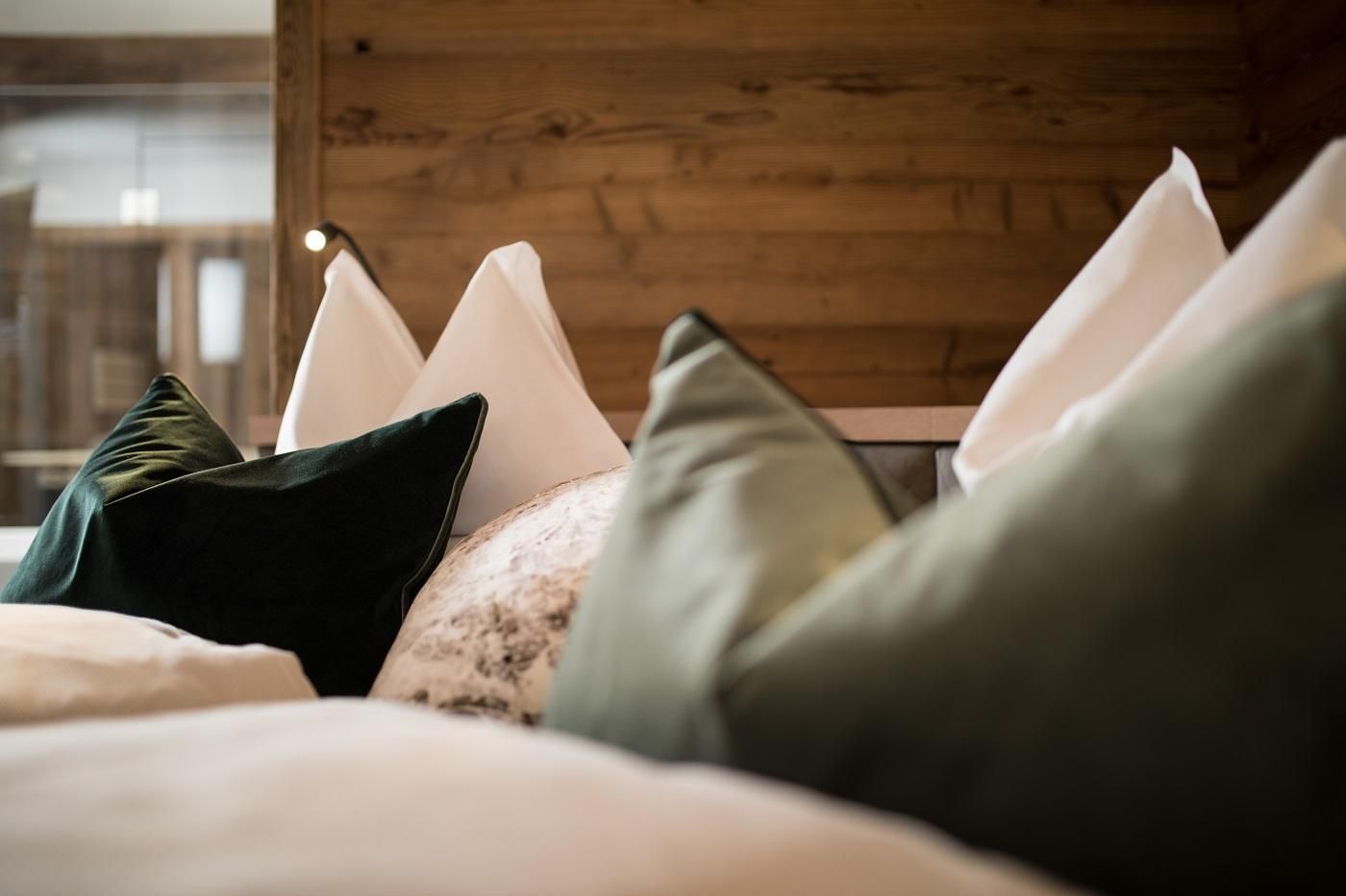 A cozy array of cushions in various colors and textures. In the background, wooden paneling can be seen, creating a warm atmosphere.