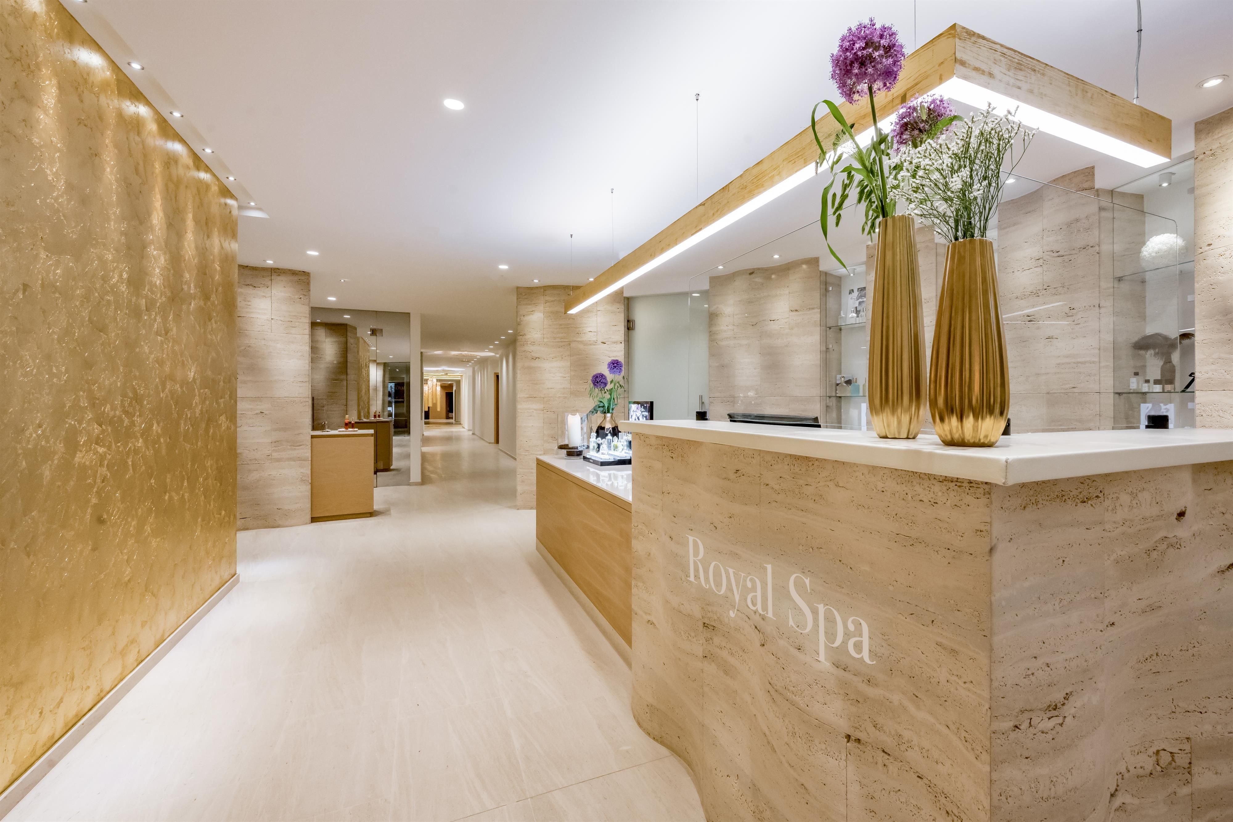 An elegant reception area of a spa with a bright, modern design. Vases with flowers give the room an inviting atmosphere.