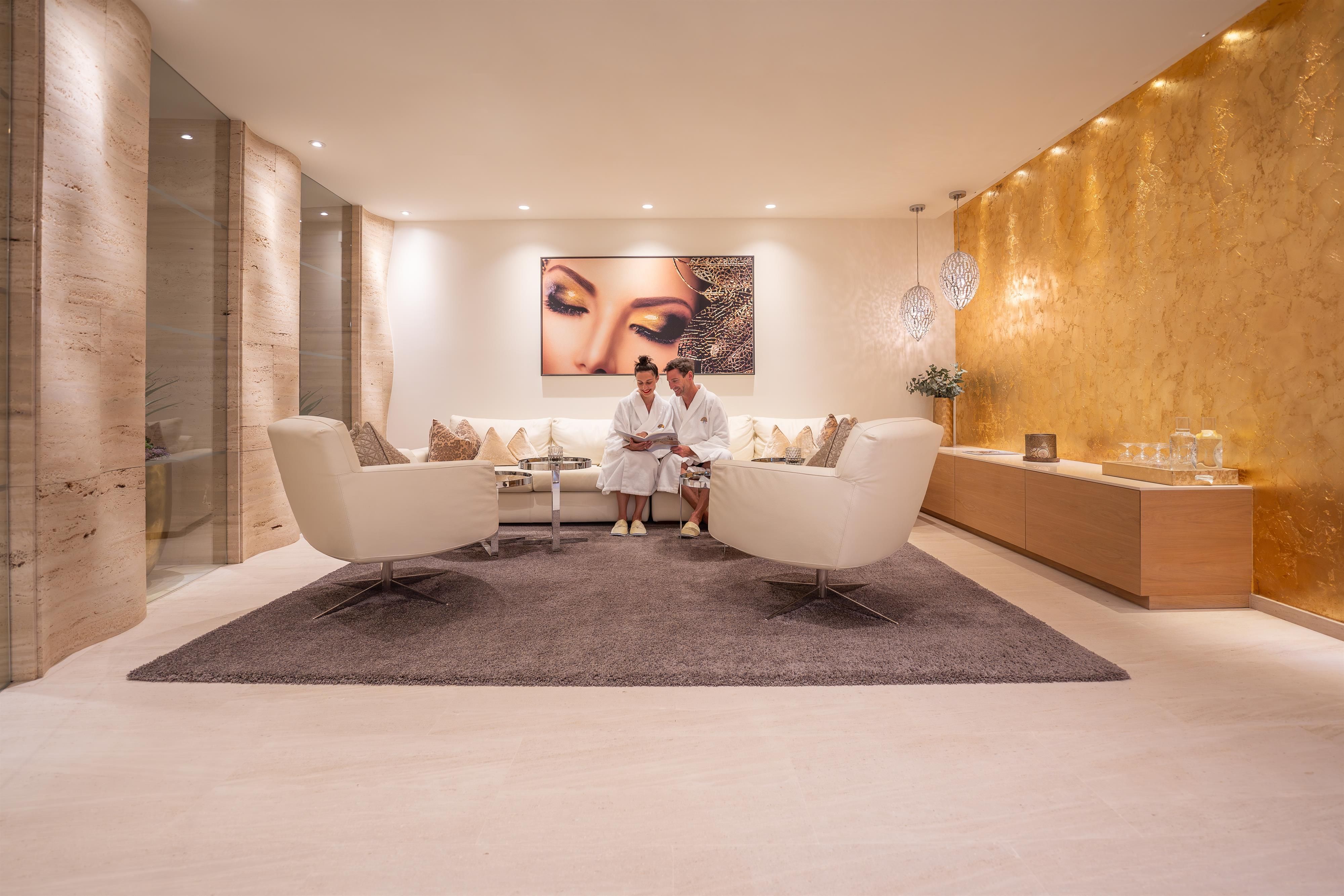 An elegant wellness area with modern furniture and soft colors. Two people in bathrobes relax in the cozy atmosphere.