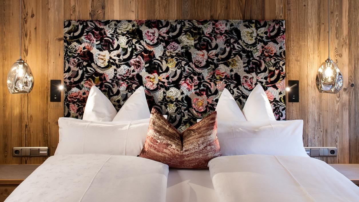 A stylish bedroom with an elegant headboard made of colorful fabric. The cushions and the modern lamps create a cozy atmosphere.