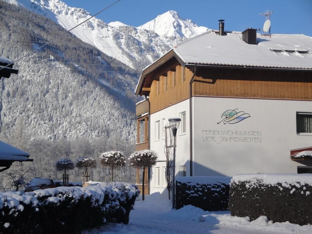 A winter village with snow-covered houses and high mountains in the background. The scene exudes a calm and idyllic atmosphere.