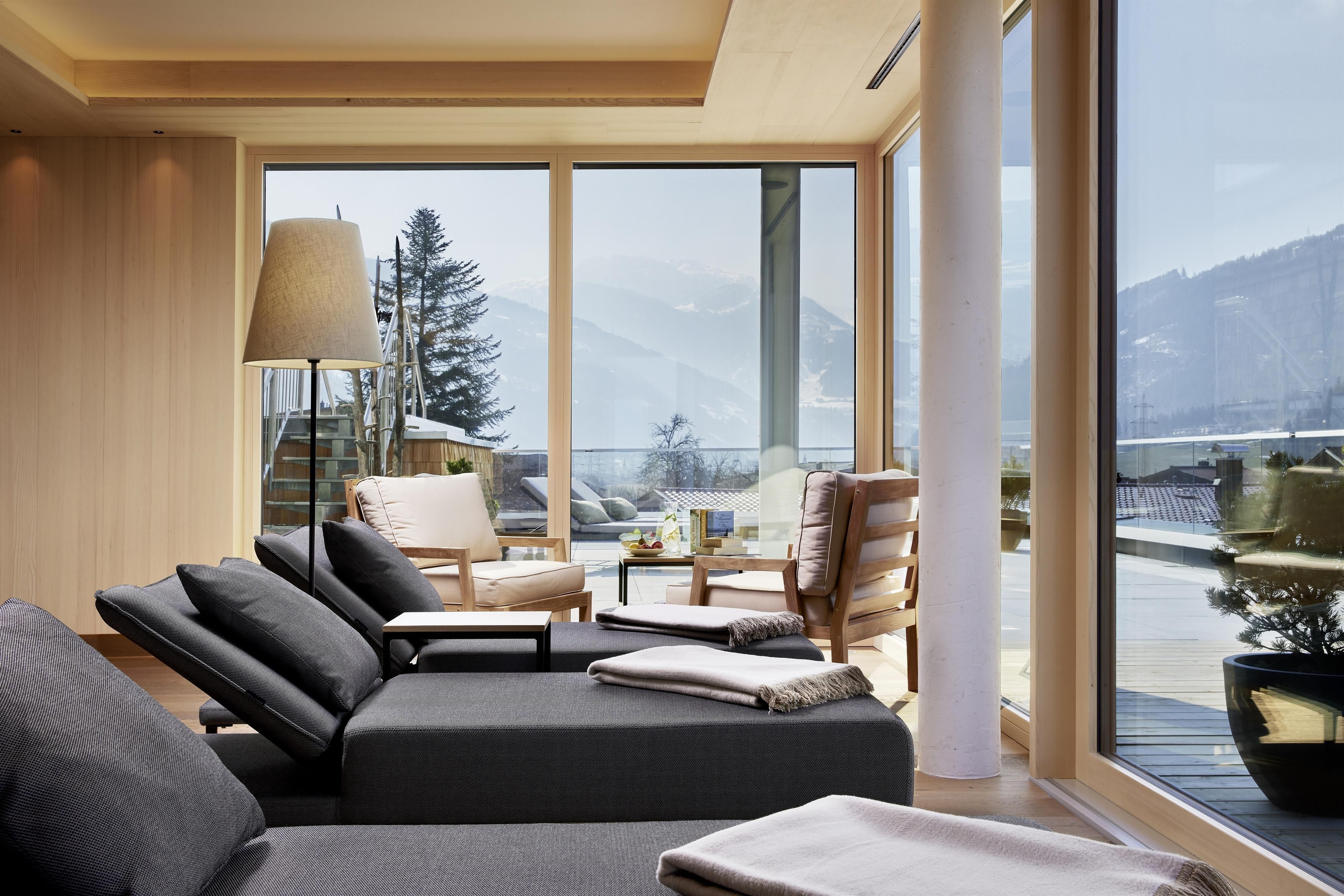 A modern living room with large windows that offer a view of the mountains. The relaxing decor invites you to linger.