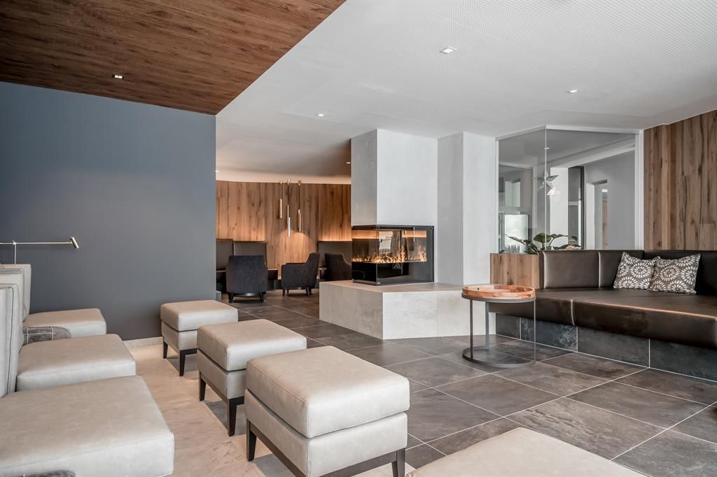 A modern lounge area with comfortable seating and a fireplace. The room has a bright, inviting atmosphere with wood and stone accents.