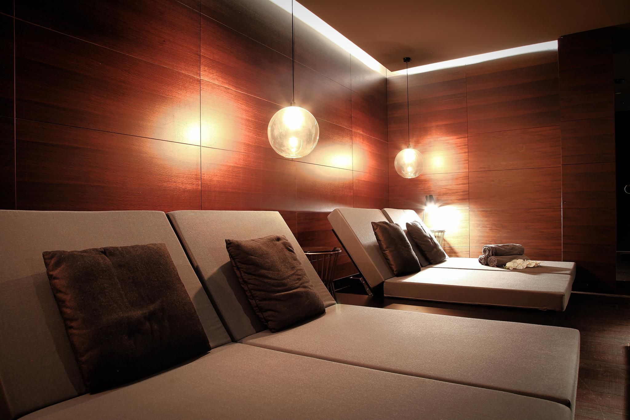 An elegant relaxation area with cozy loungers and soft lighting. The wooden paneling creates a warm and calm atmosphere.