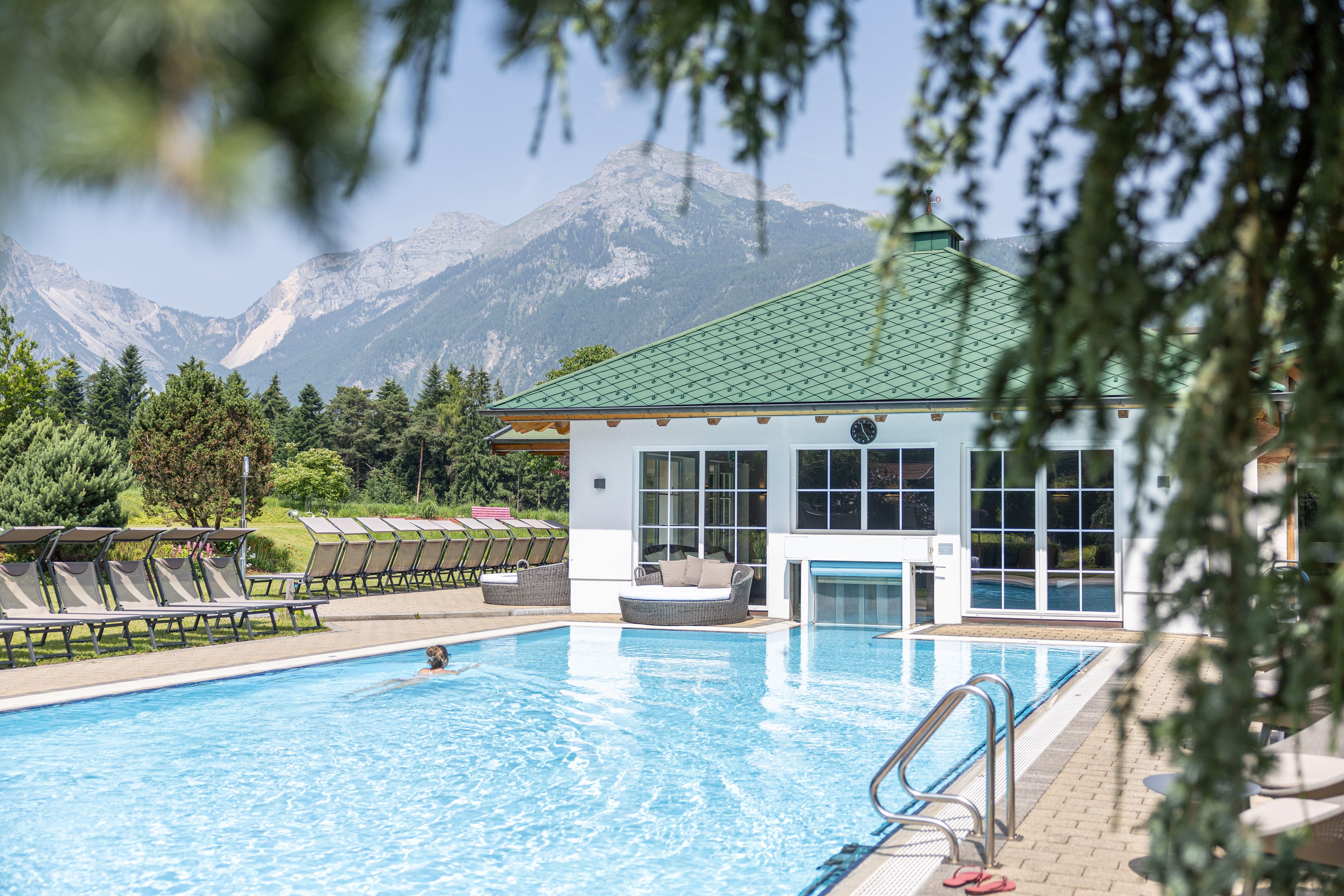 An inviting pool amidst a picturesque landscape with mountains in the background. Relaxed loungers are ready to enjoy the sun.