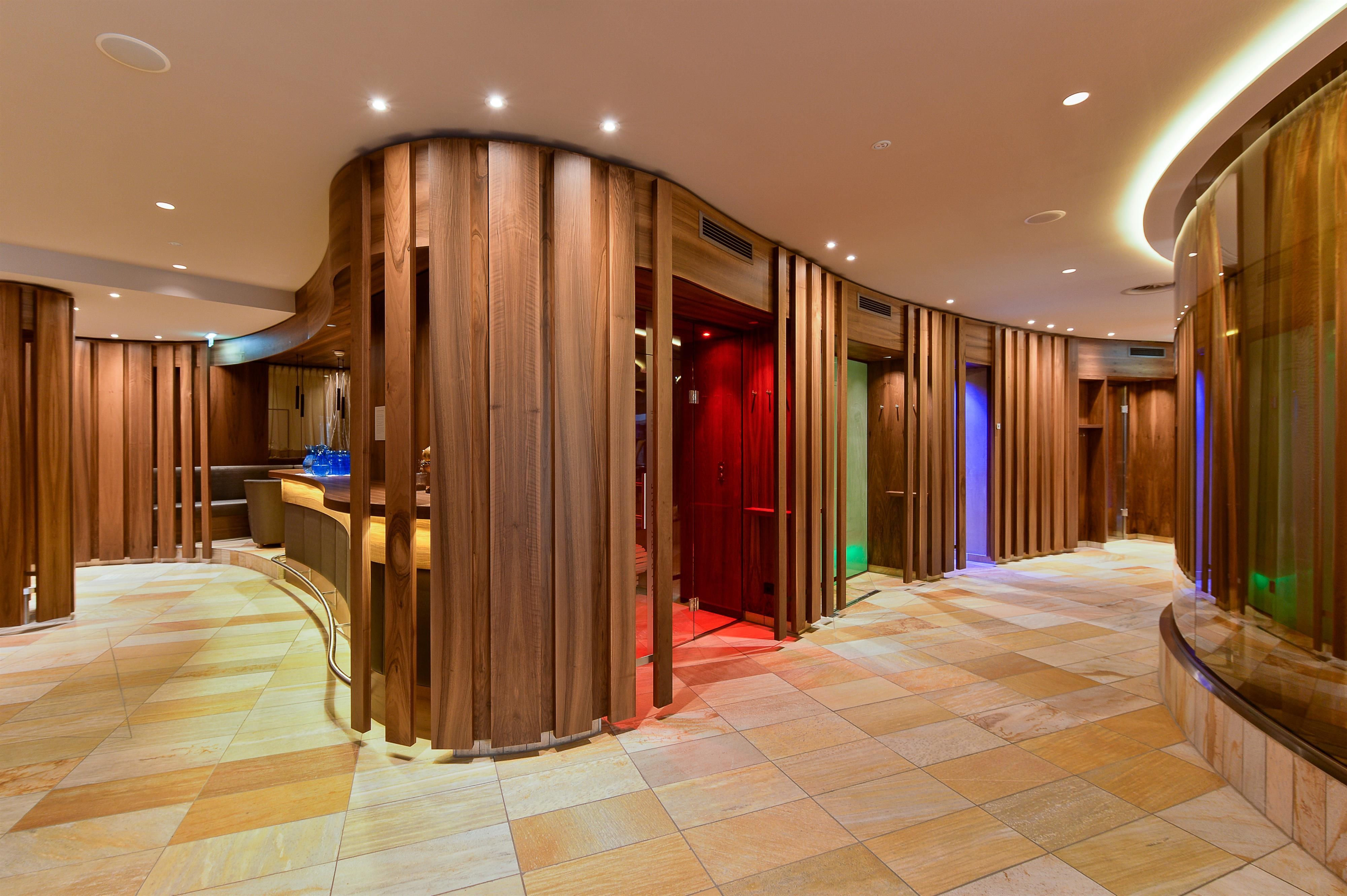 An elegant interior with wood paneling and soft lighting. The room has curved walls and a modern atmosphere.