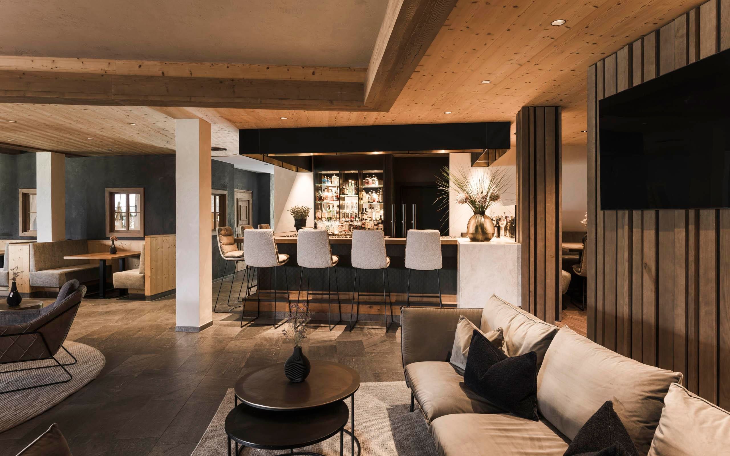 A modern living room with a cozy couch and a fireplace. Large windows offer a view of the outer landscape.