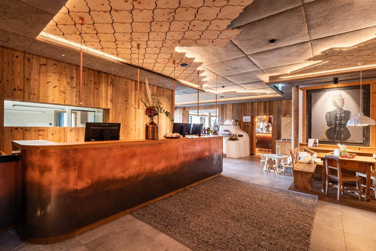 A stylish reception area with wooden paneling and an elegant reception desk. The room is bright and modern, featuring a cozy dining area.