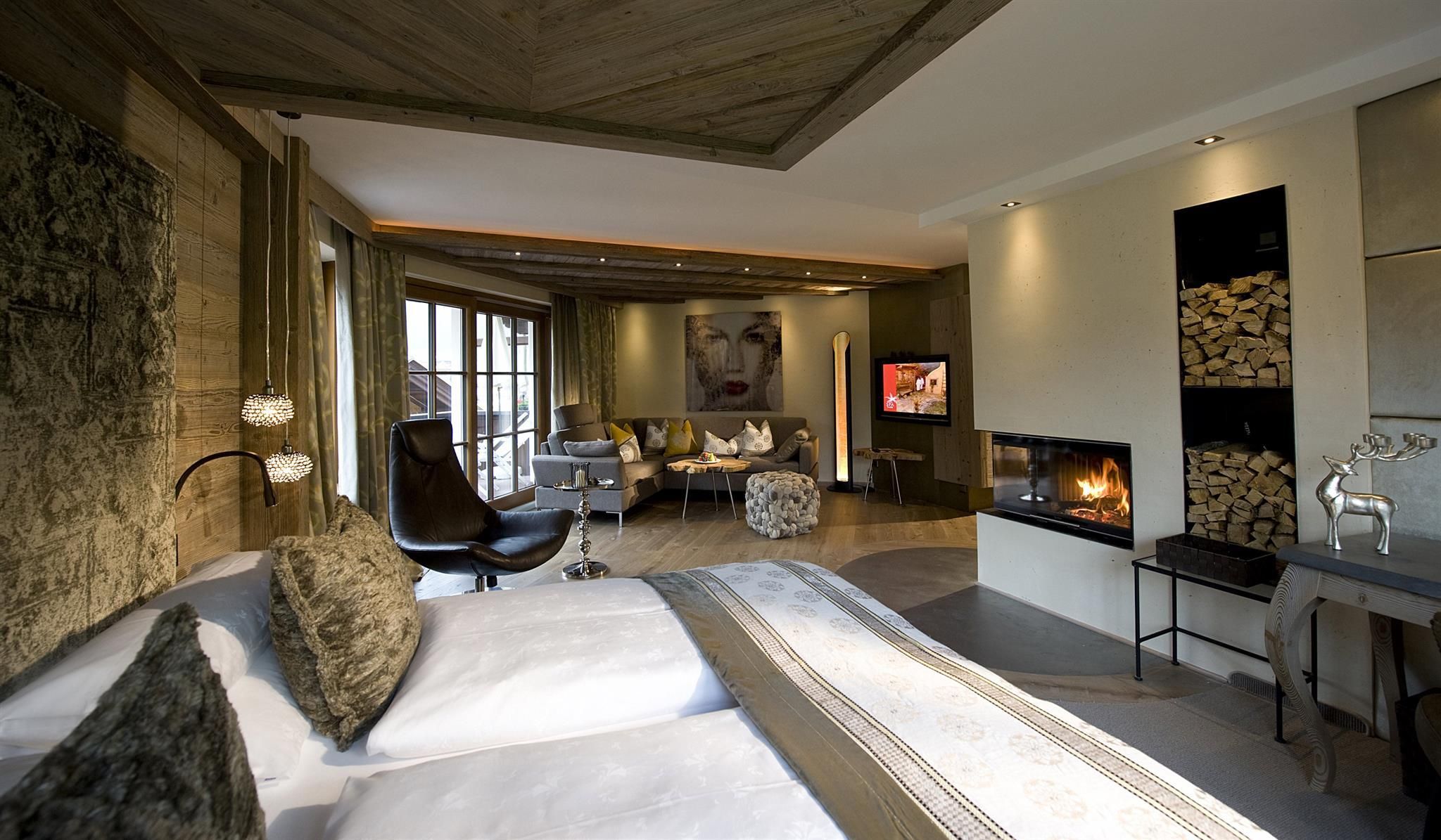 A modern bedroom with a cozy bed and a fireplace. The room is stylishly furnished and offers a view of the surroundings.