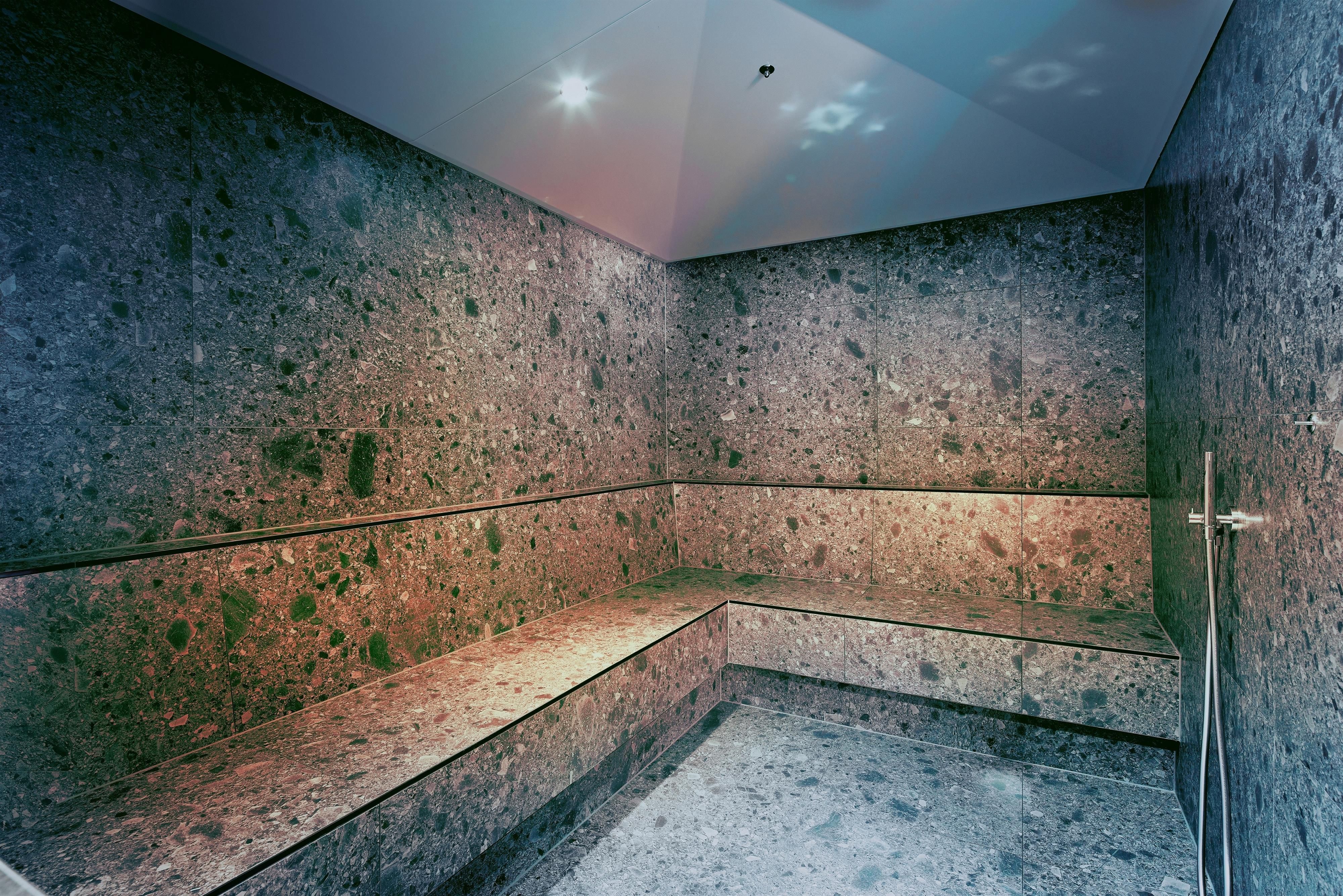 A modern wellness area with stone walls and benches. Soft light creates a relaxing atmosphere.