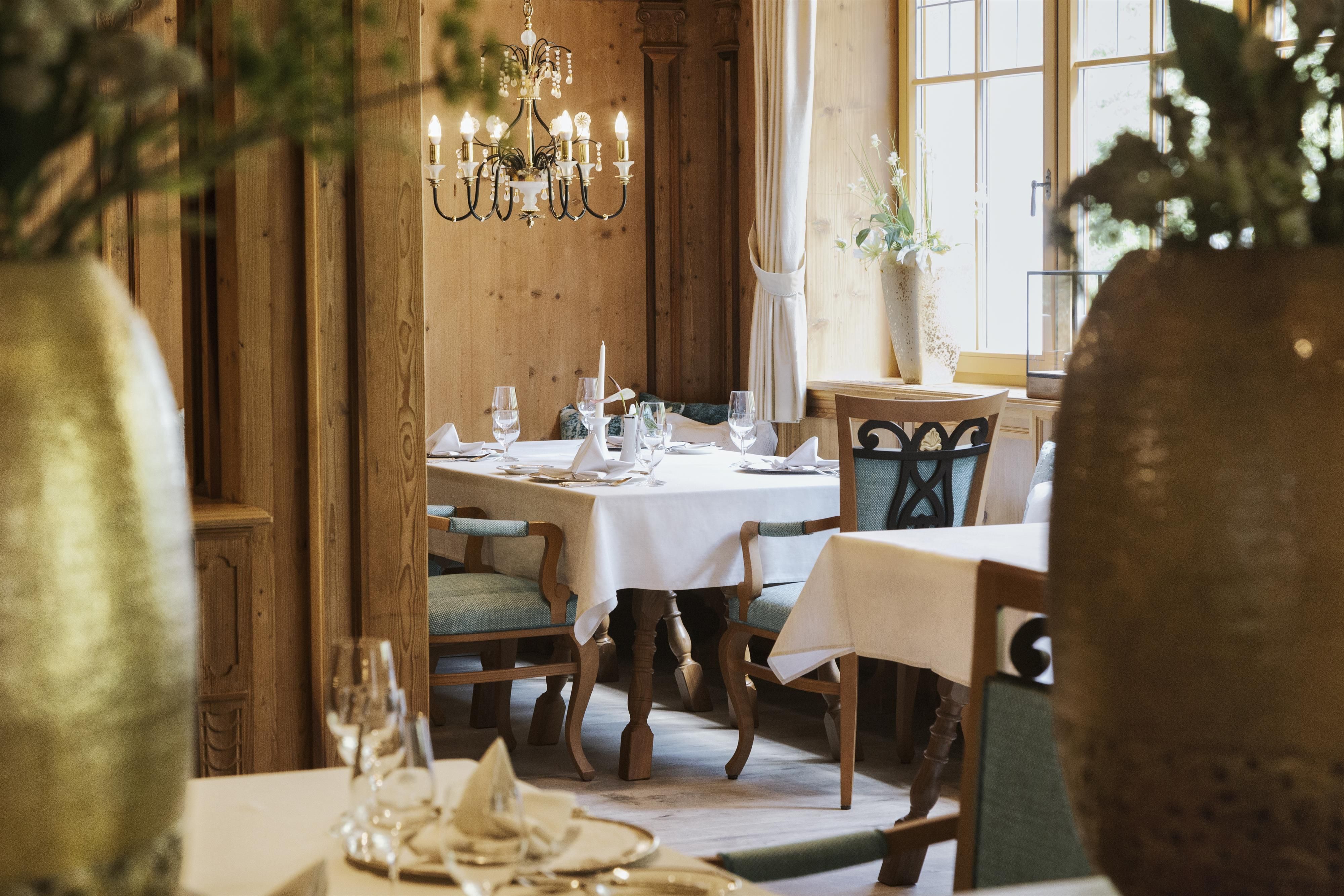 An elegant restaurant with wooden walls and a festively set table. Beautiful decorations and a chandelier can be seen in the background.