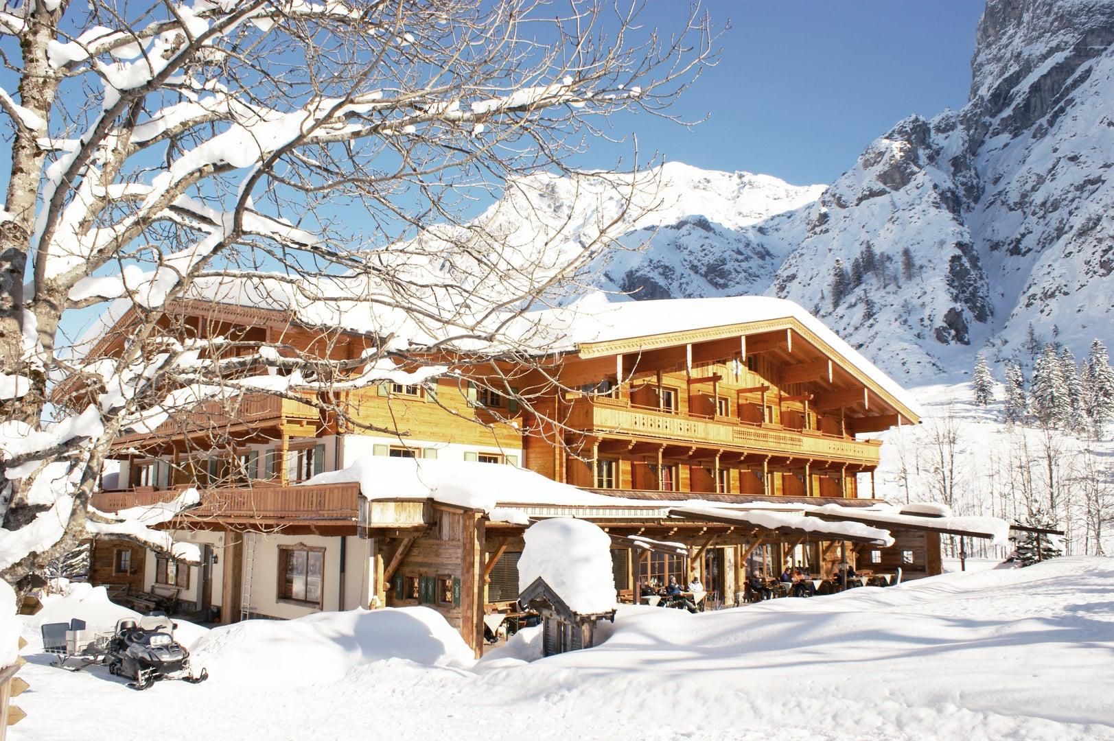 A cozy hotel amid a snow-covered landscape. The surrounding mountains and the clear sky give the scene an idyllic atmosphere.