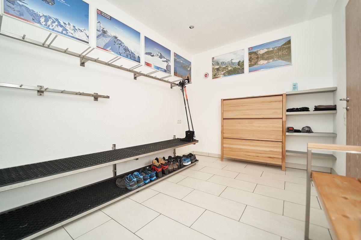 A modern entrance area with shoe racks and a wooden dresser. Pictures of mountain landscapes hang on the walls.