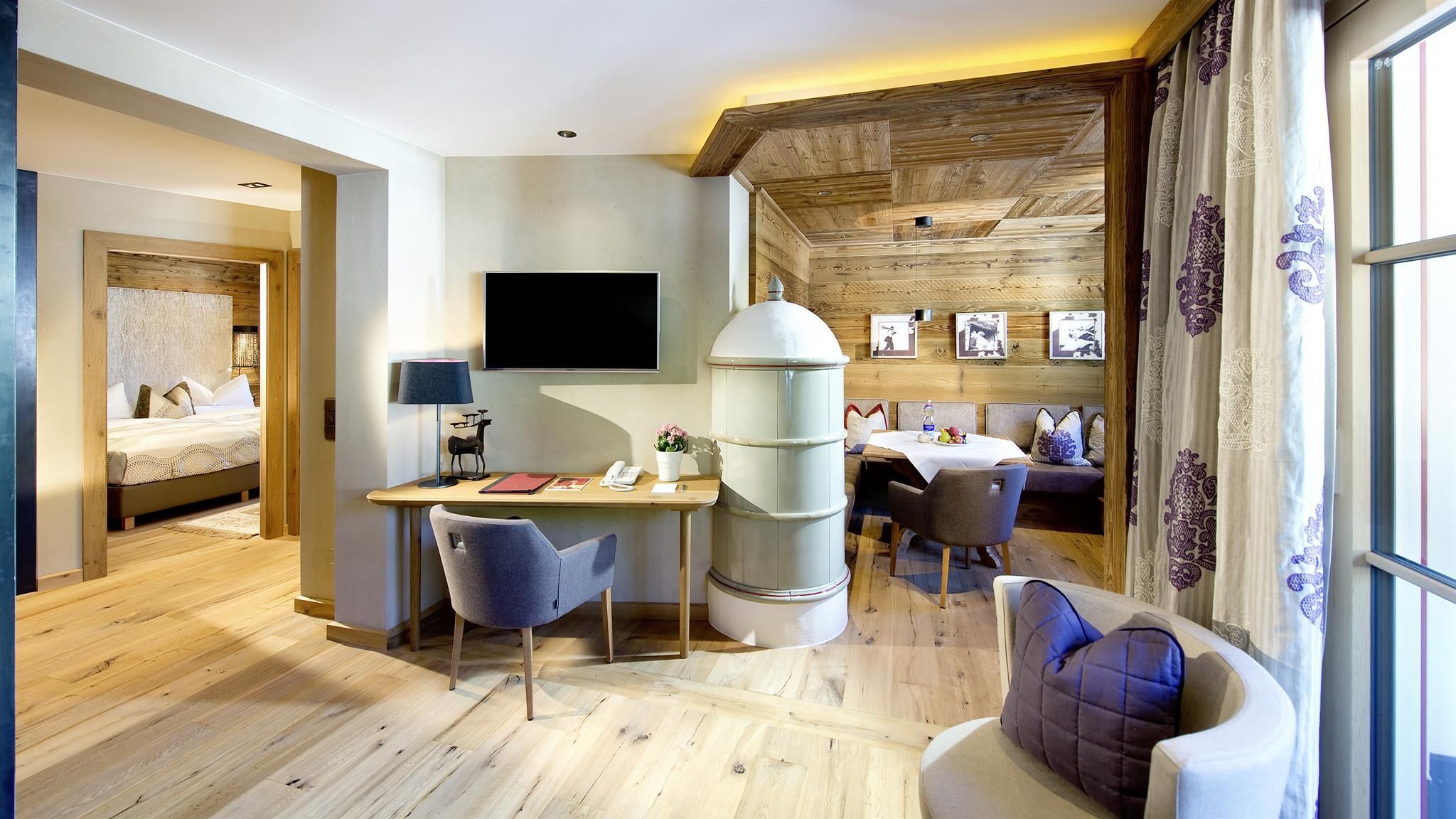 A modern room with wooden walls and elegant design. There is a table, chairs, and a flat-screen television.
