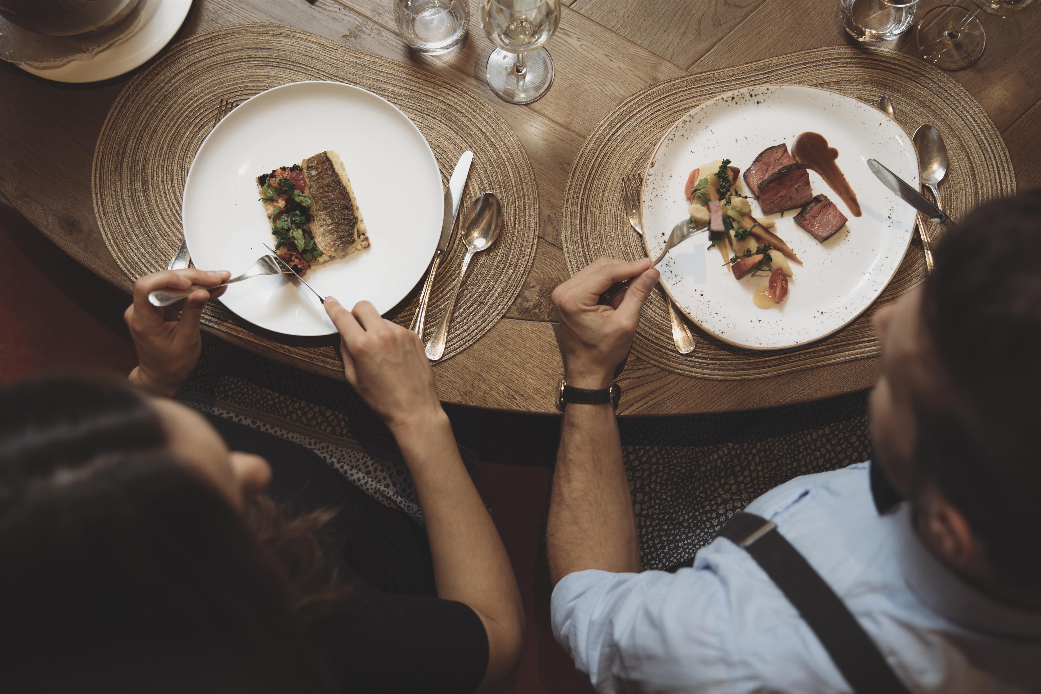 An elegant meal with two place settings on a round table. The plates showcase a diverse selection of dishes that are carefully arranged.