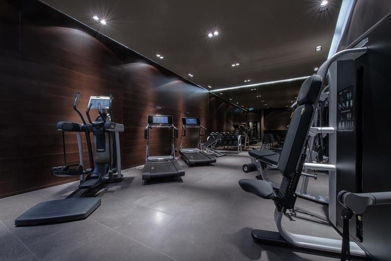 A modern gym with various training equipment. The environment is kept dark and well-lit.