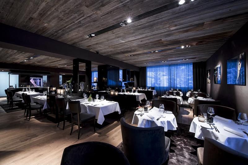 An elegant restaurant with dim lighting and stylishly set tables. The modern decor creates a cozy atmosphere.