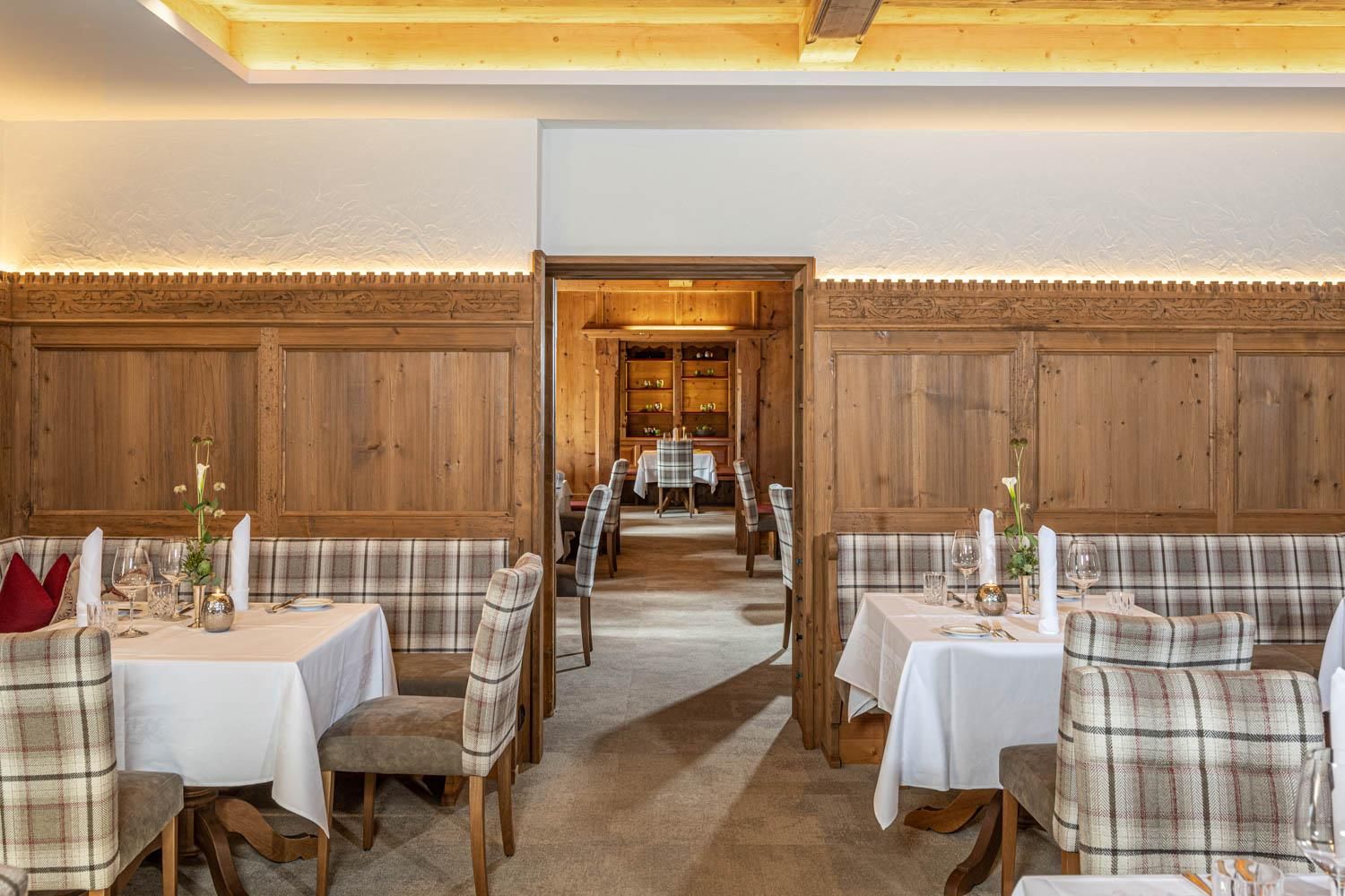 An inviting restaurant with rustic wooden interiors. The tables are elegantly set and invite you to linger.