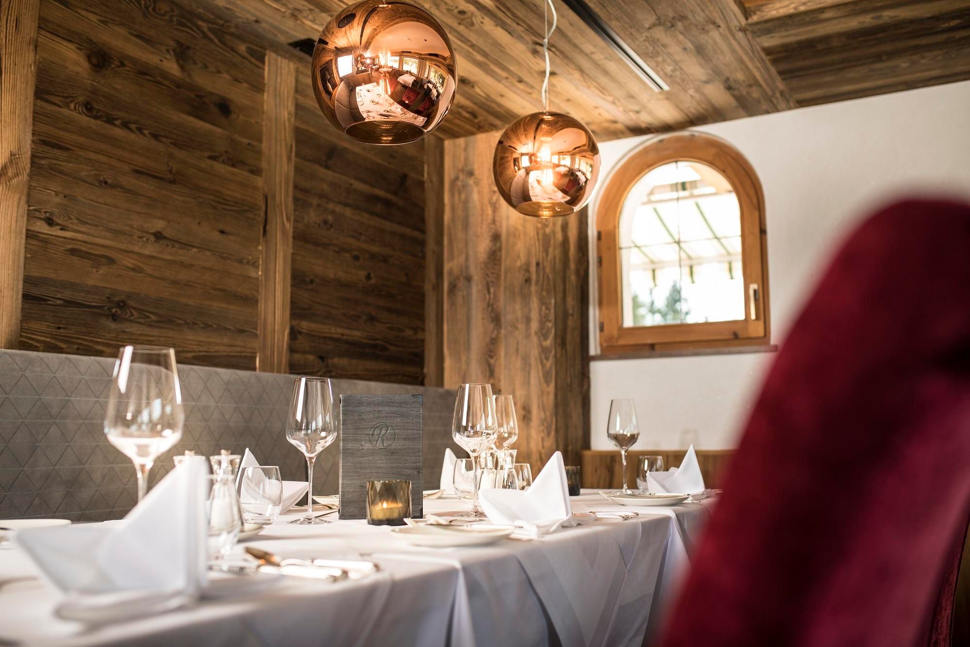 An elegant restaurant with wooden walls and a tastefully set table. The warm lighting creates an inviting atmosphere.