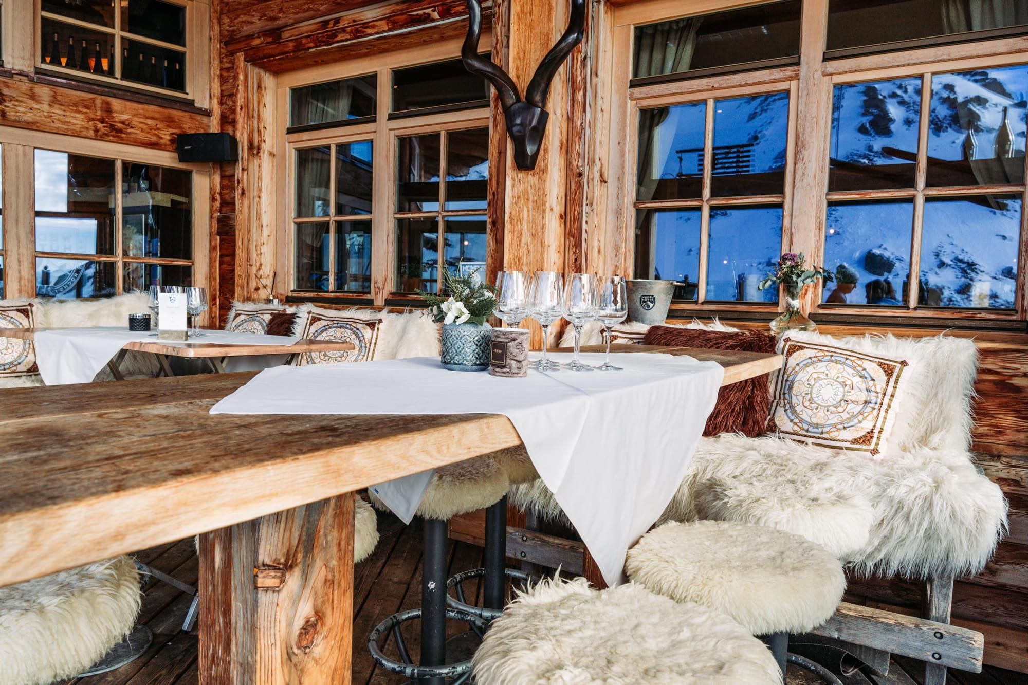 A cozy restaurant with wooden walls and large windows.
Tables are elegantly set and outfitted with lambskins.