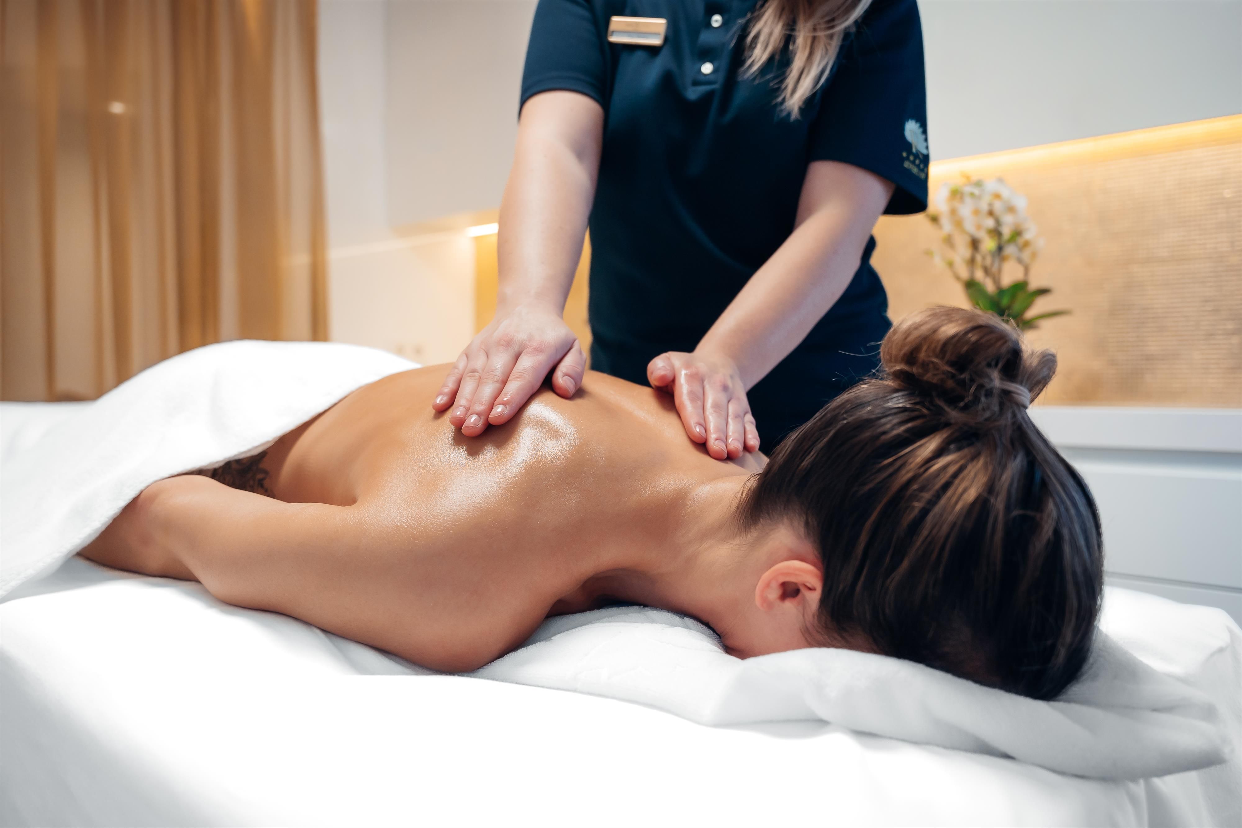 A woman receives a relaxing back massage in a modern wellness area. The atmosphere is calm and pleasant.