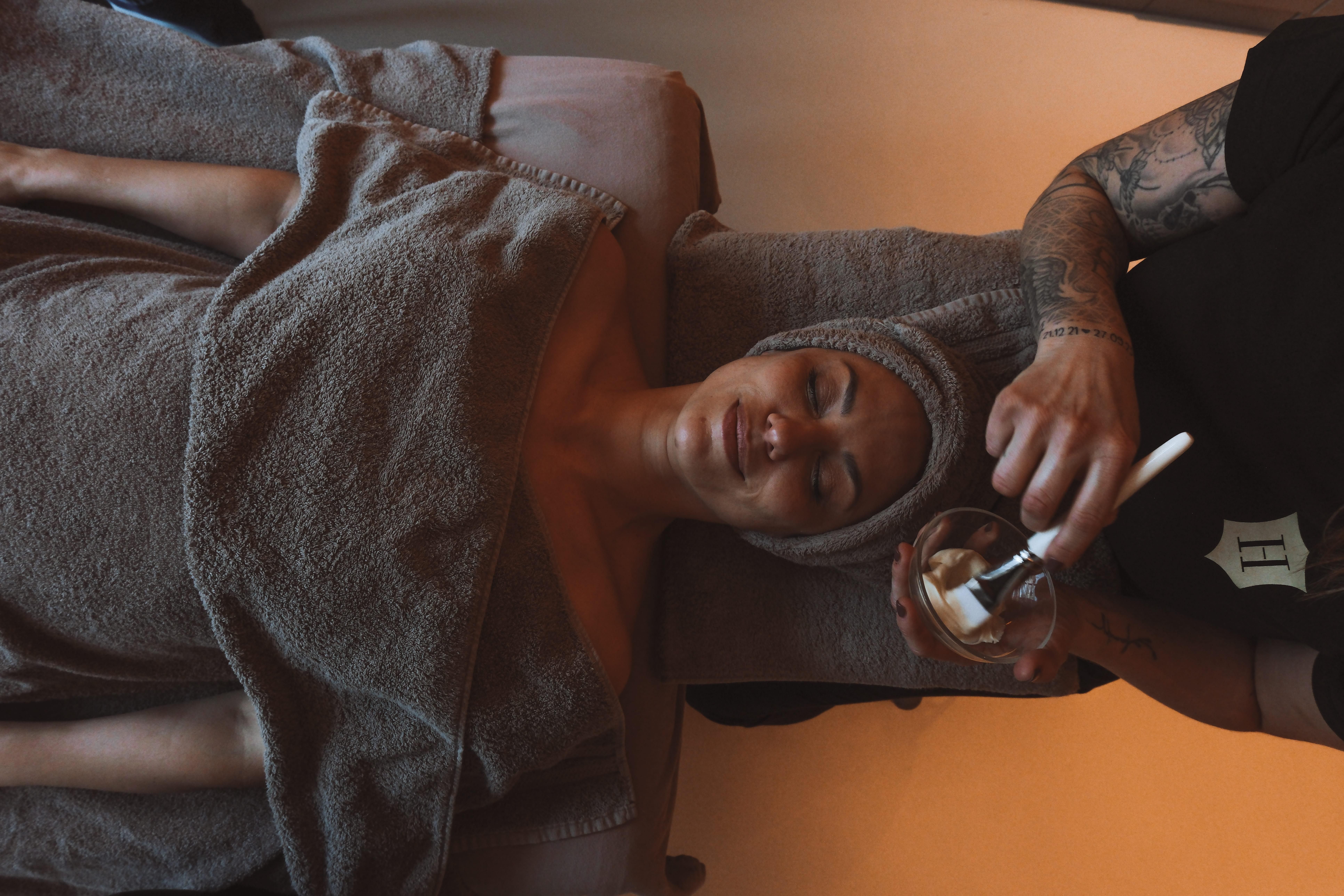A relaxing spa treatment for a woman lying on a treatment chair. A specialist is applying a facial mask.