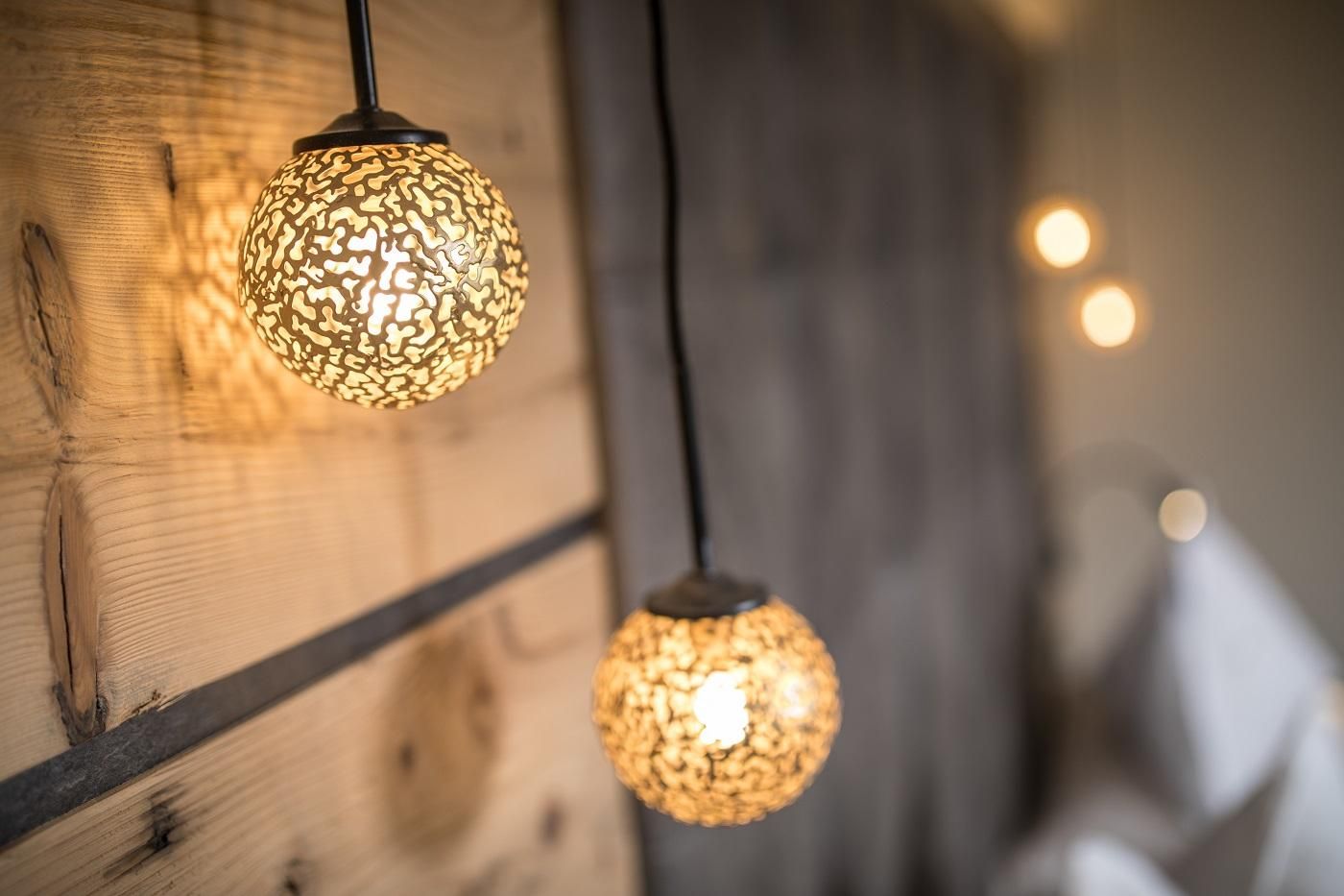 Two decorative light spheres hang on a wooden wall. They emit warm light and give the room a cozy atmosphere.