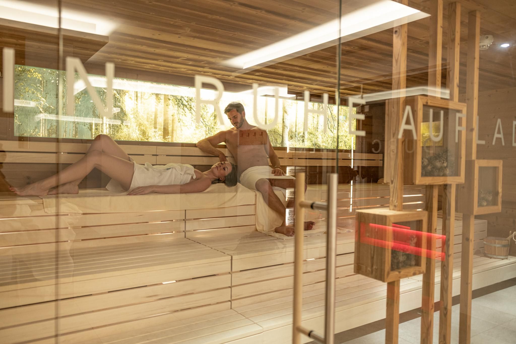 A modern sauna with wood paneling and relaxing guests. Soft lighting and a calm ambiance create a relaxing atmosphere.