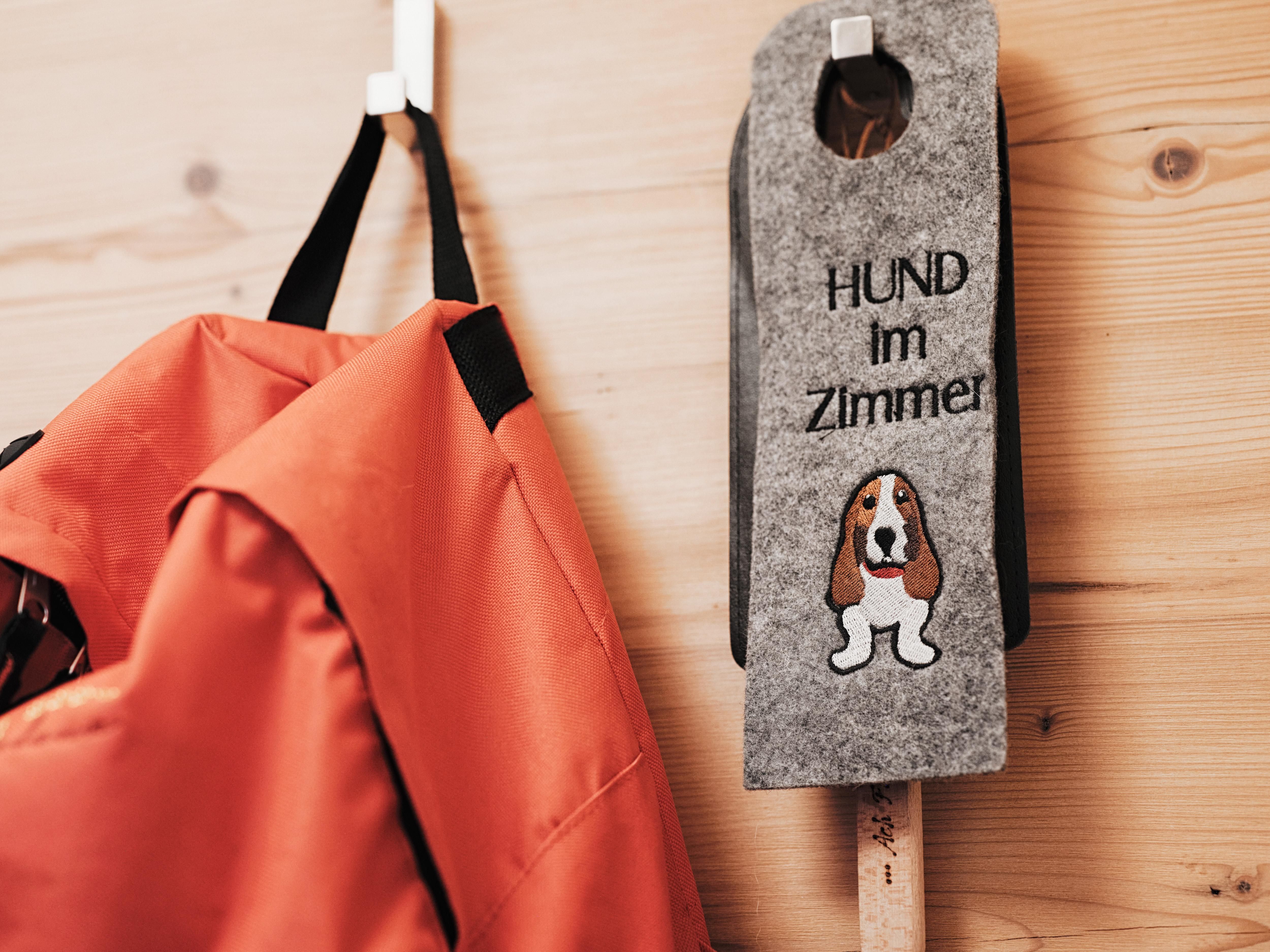 An orange bag hangs on a hook. Next to it is a sign that reads "DOG in the room" with a picture of a dog.