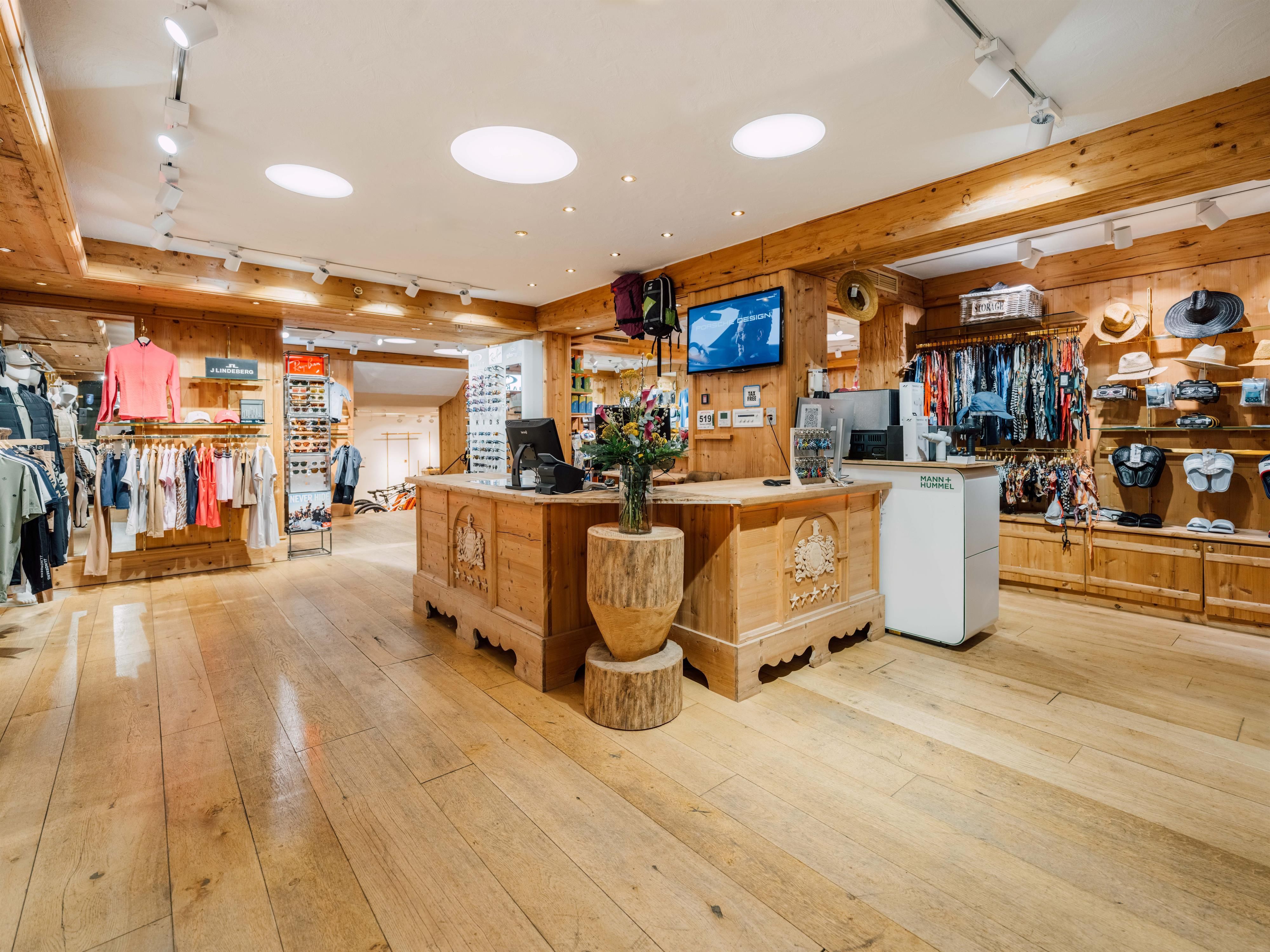 A modern sportswear store with wooden interiors. Various clothing items and accessories are neatly displayed.