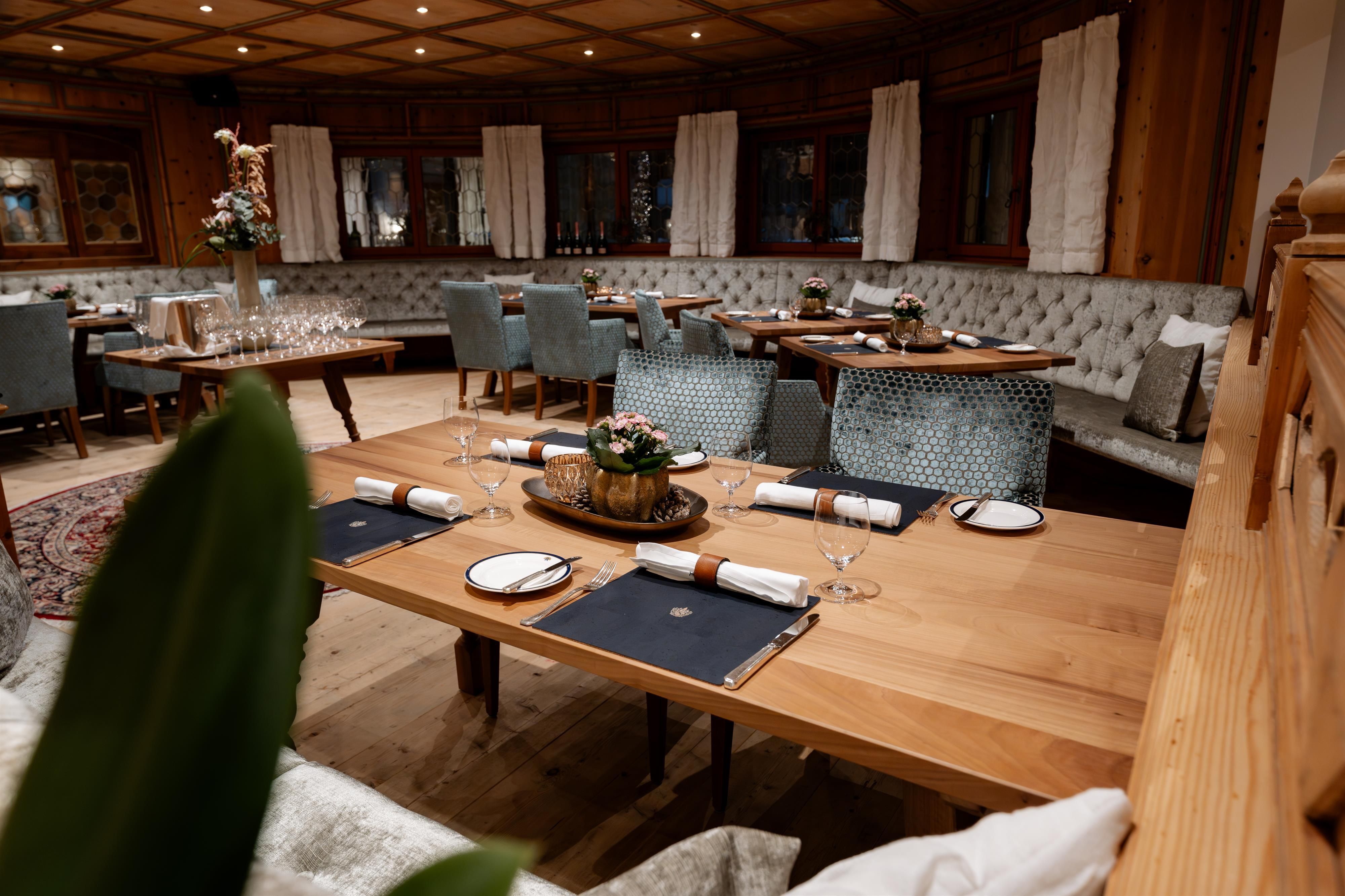An elegant restaurant with wooden paneling and stylish furniture. Tables are lovingly set and the atmosphere is inviting.