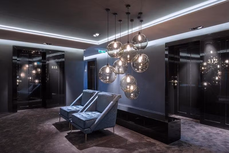 A modern hotel lobby with elegant wall switches and stylish pendant lights. Two cozy armchairs invite you to relax.