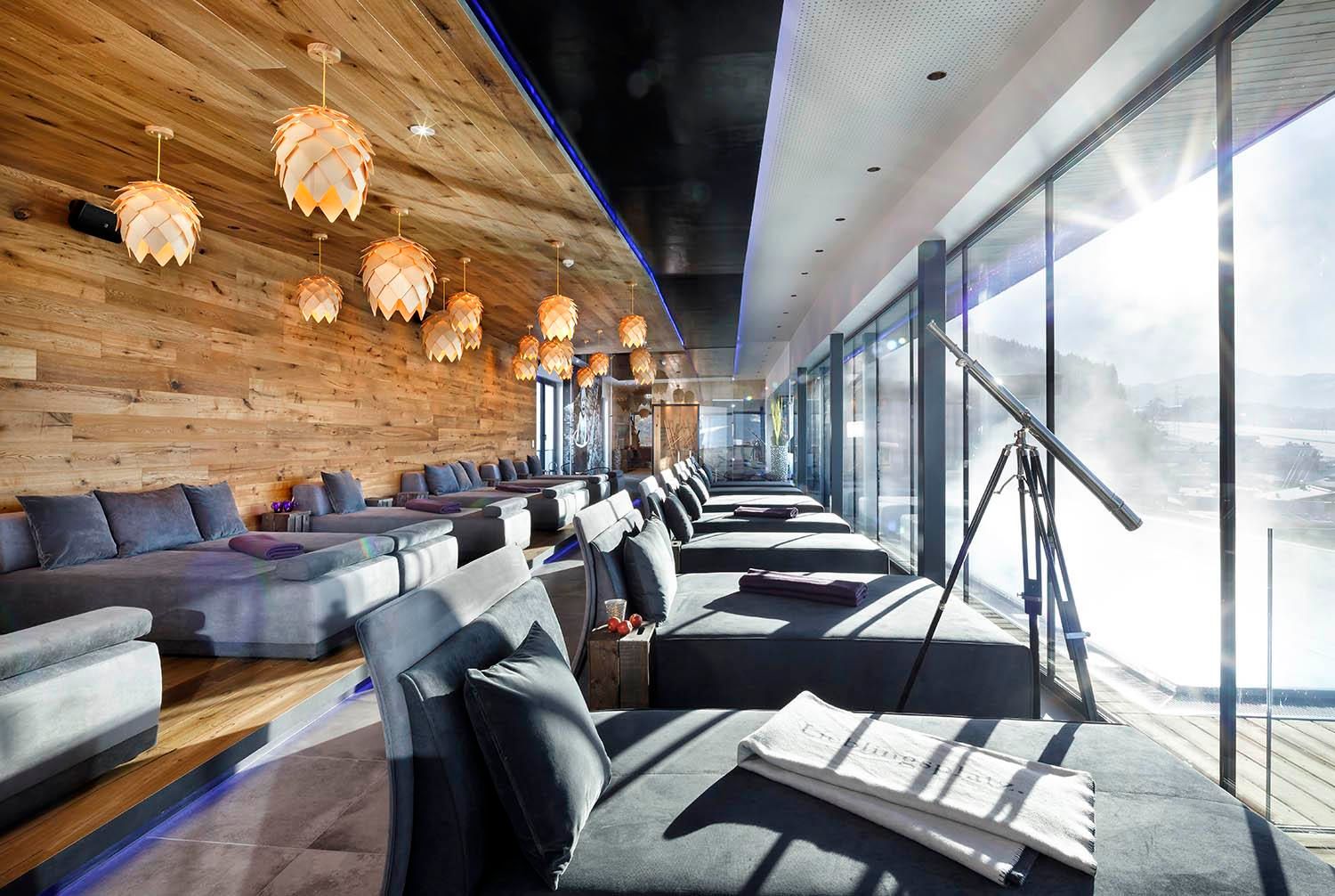 A modern spa with wooden paneling and cozy loungers. Large windows offer a view of the surroundings and flood the room with natural light.