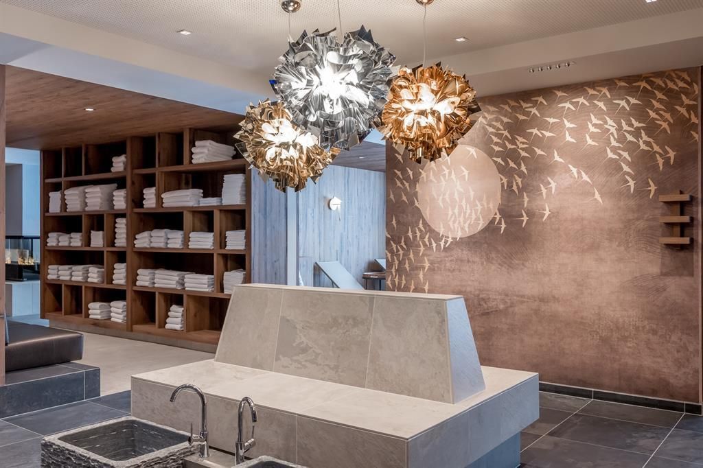 An elegant spa area with modern lighting and wall decor. Soft towels are neatly stacked, and the room exudes tranquility.