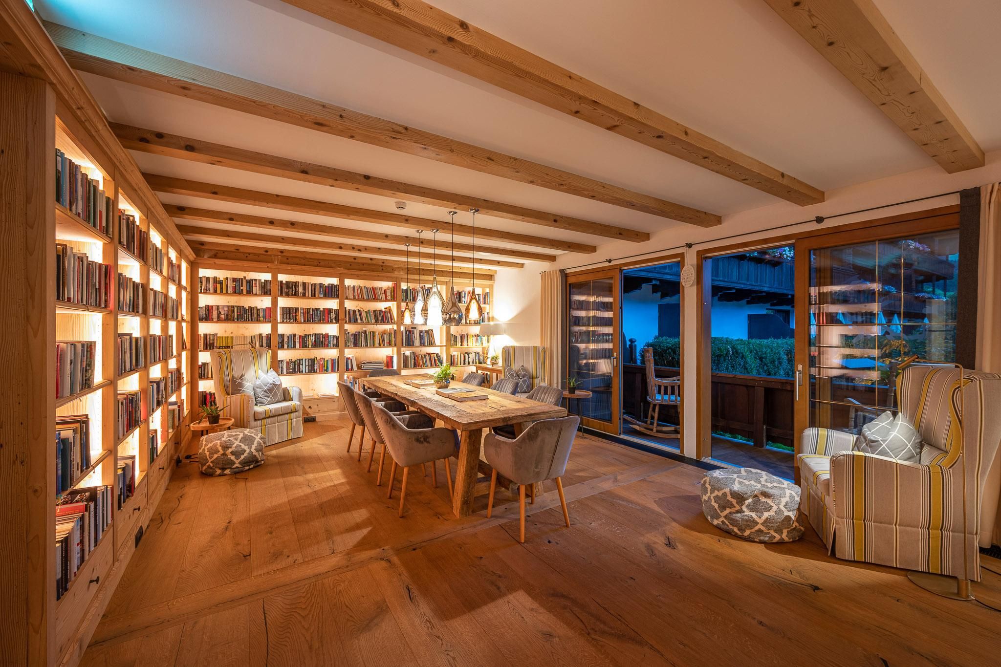 A cozy room with a bookshelf and a long dining table.
Large windows let in plenty of light and offer a view outside.